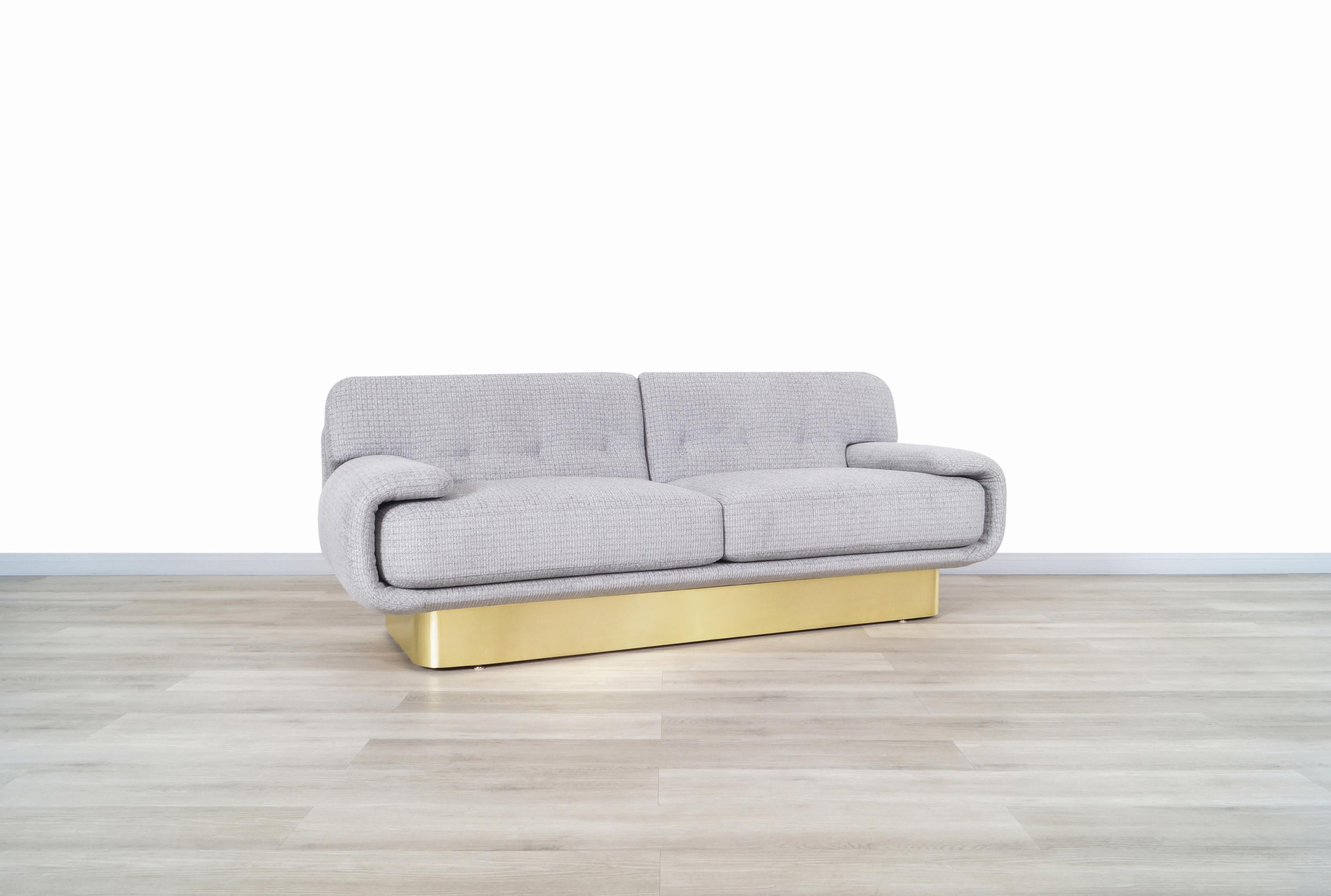 Fabulous Mid-Century Modern sofa designed in the United States, circa 1970s. Features an innovative design where the structure of the sofa stands out, showcasing both sculptural armrests wrapping around the cushions. The sofa rests on a shiny