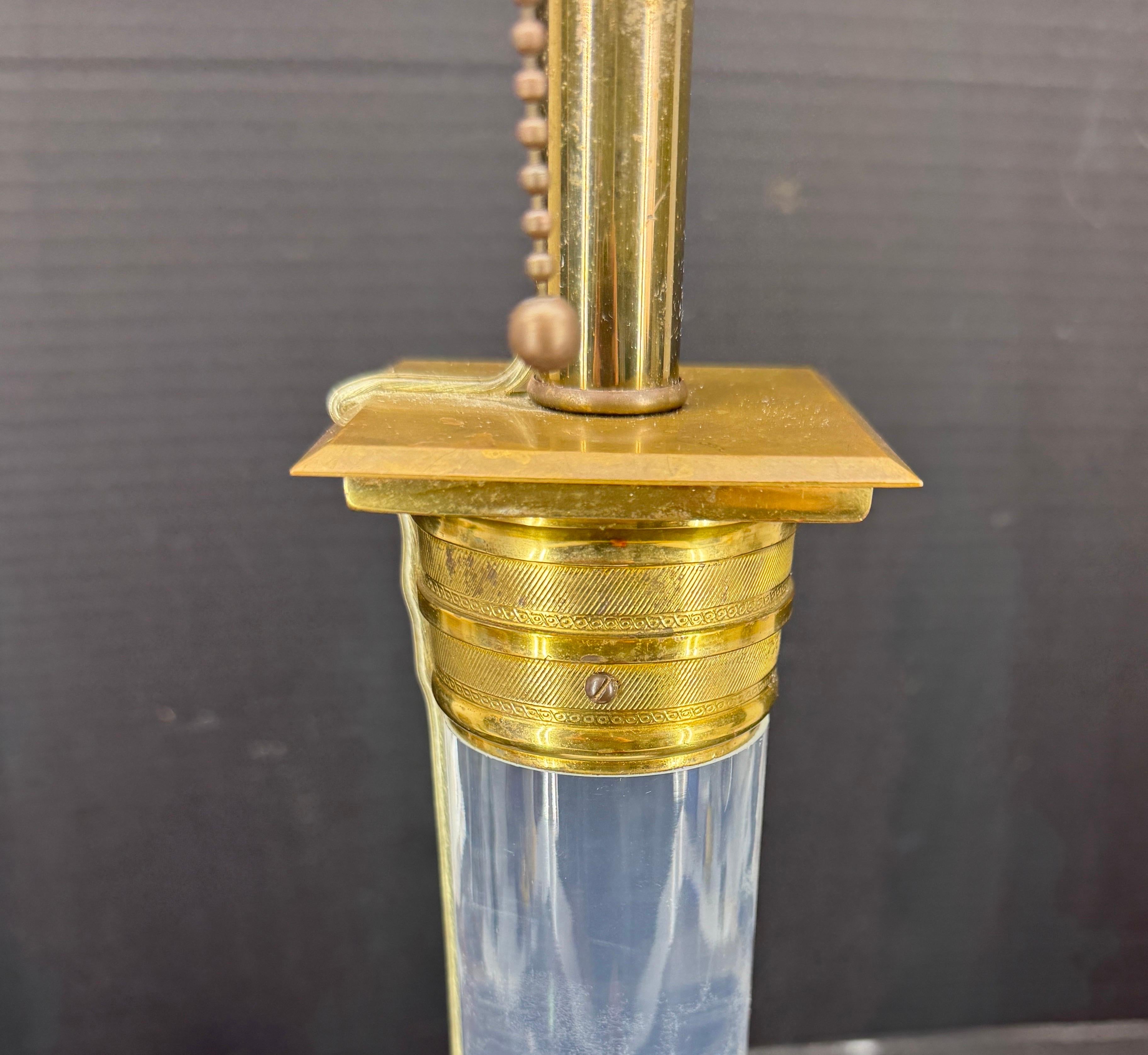 Cette lampe à colonne de l'ère moderne du milieu du siècle dernier se caractérise par sa solidité et sa robustesse. Cette lampe de table est dotée d'une épaisse colonne en lucite et d'une base carrée. La lampe est ornée d'accessoires en laiton et en