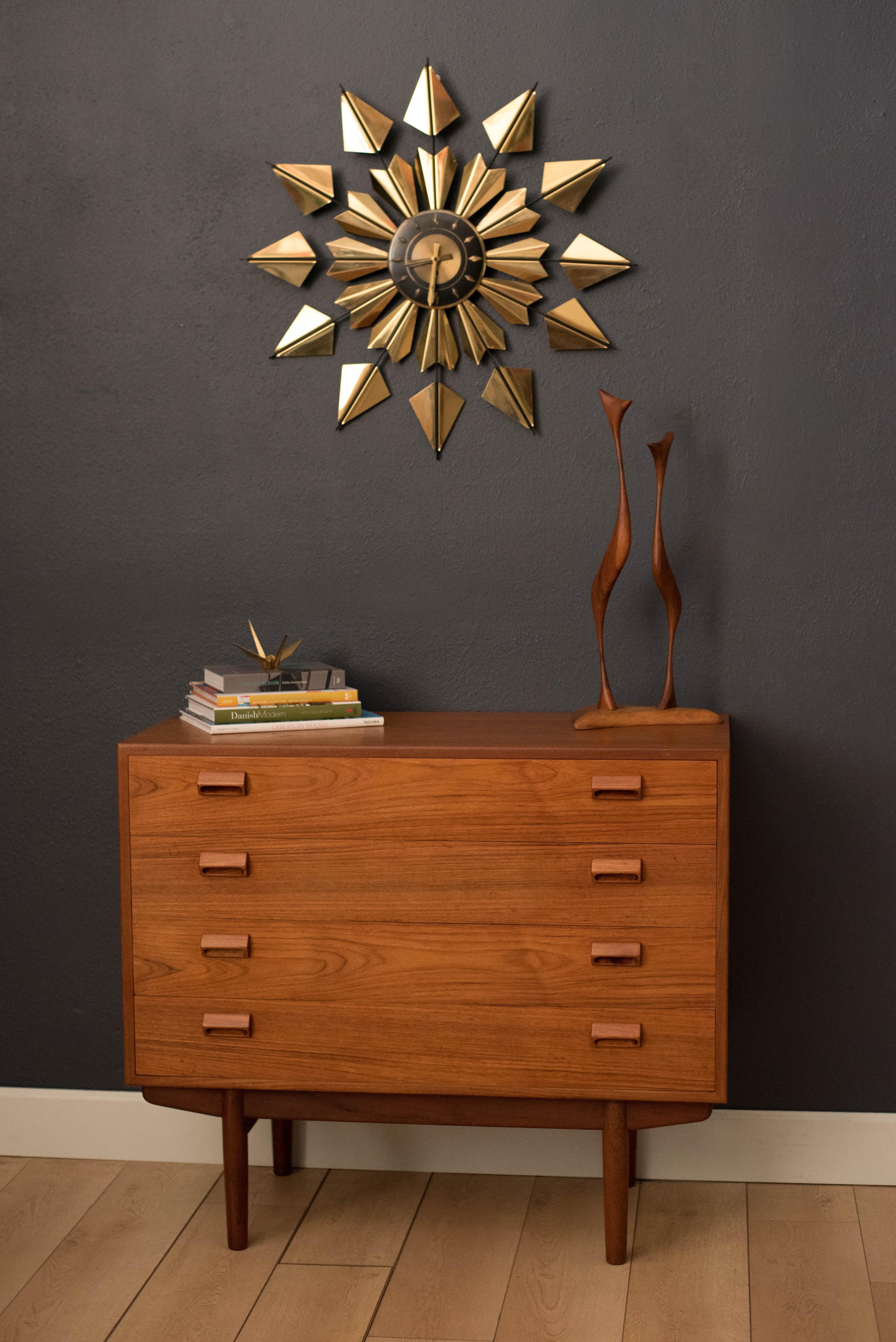 Midcentury sunburst clock in brass, circa 1960s. This oversized vintage wall clock makes a bold statement in black and gold that creates a great focal point for any space. Made by Welby and includes the original wind up key.