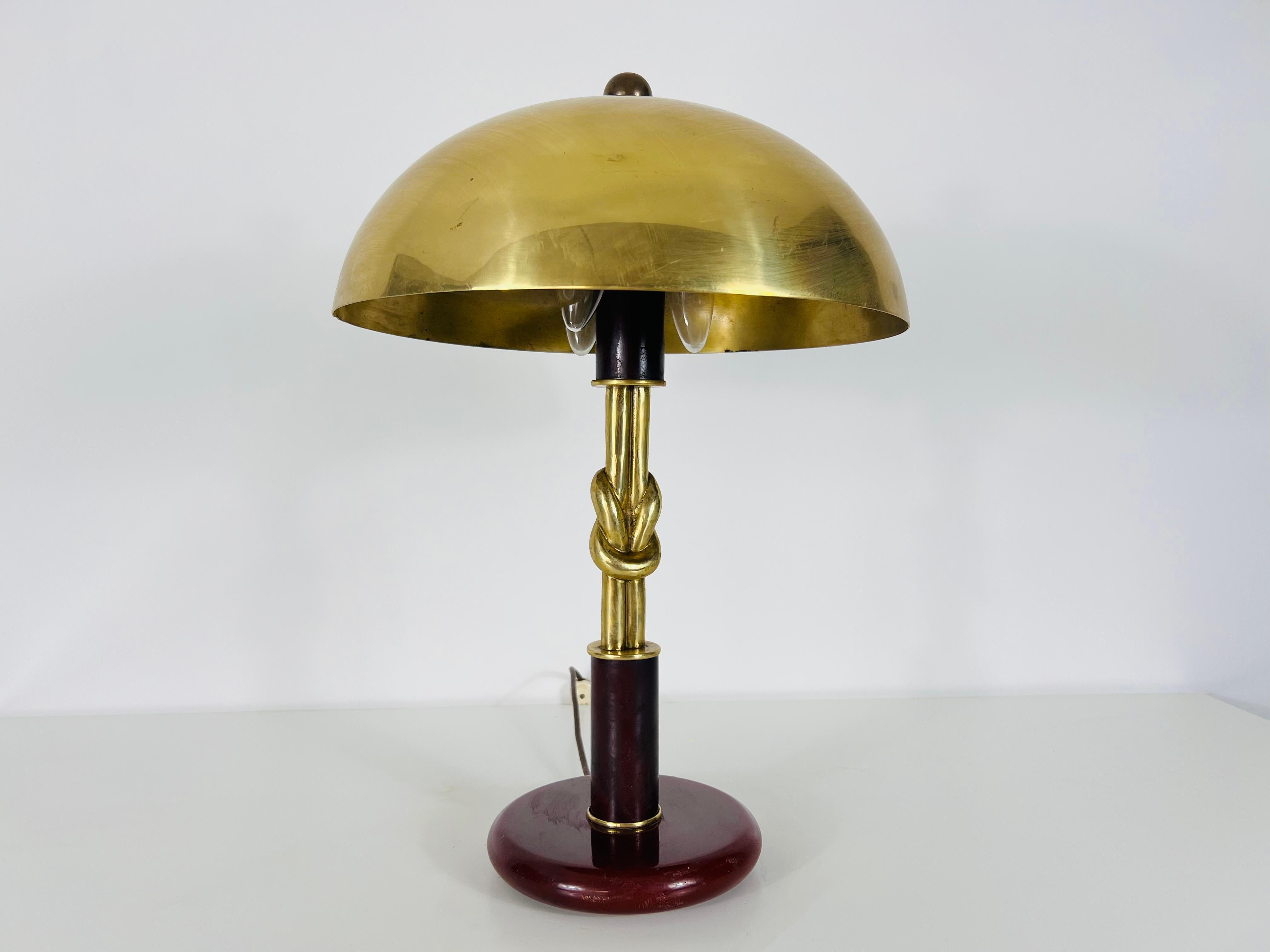 Esta exquisita lámpara de mesa de latón procede de Alemania y data de la década de 1960. Presume de un diseño elegante característico del estilo moderno de mediados de siglo, con una clara inspiración en el movimiento Bauhaus. La lámpara presenta un