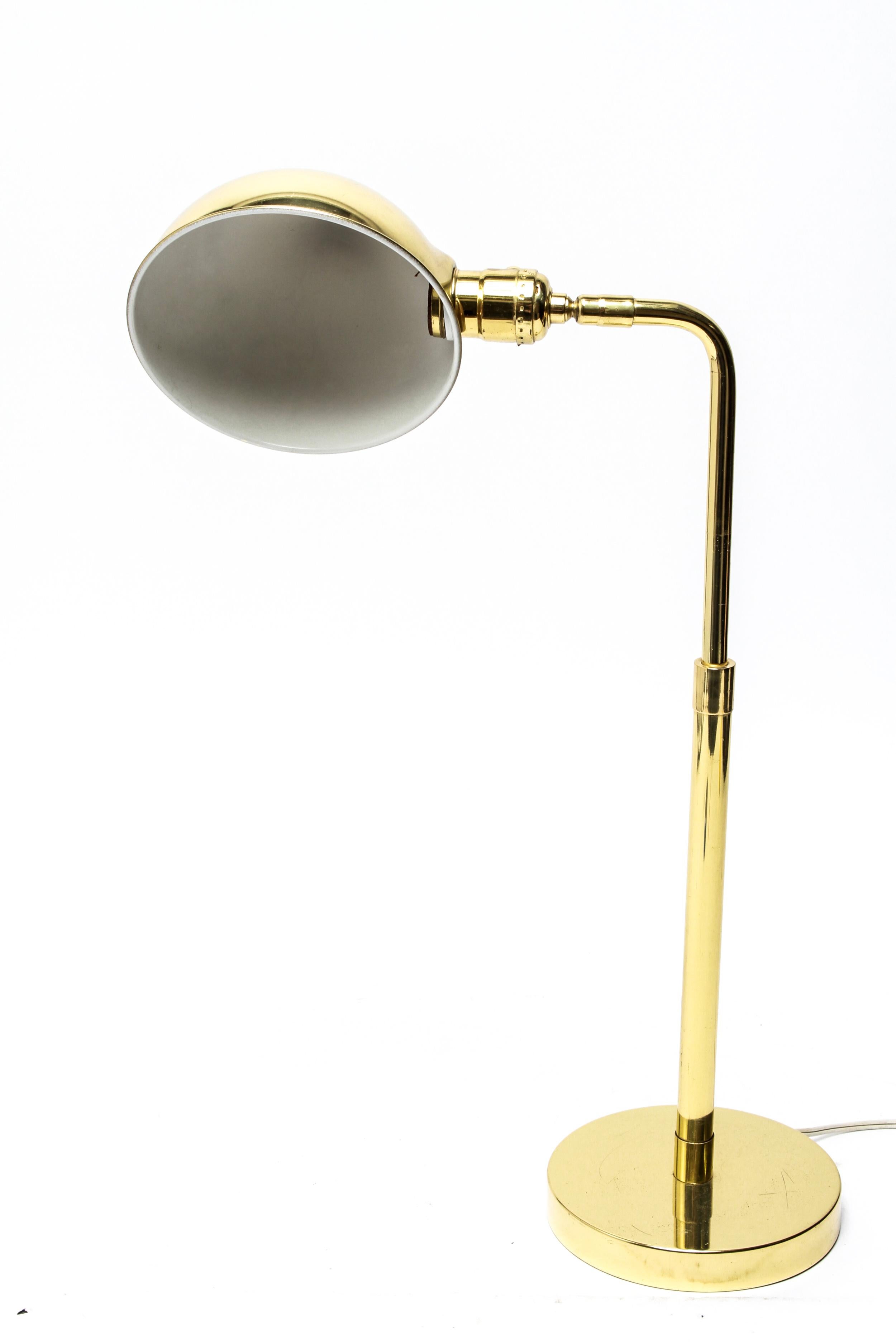Mid-Century Modern polished brass table lamp or desk lamp with a dome demilune shade. The shade interior bears a partial label. The height of the lamp can extend. In great vintage condition with age-appropriate wear.