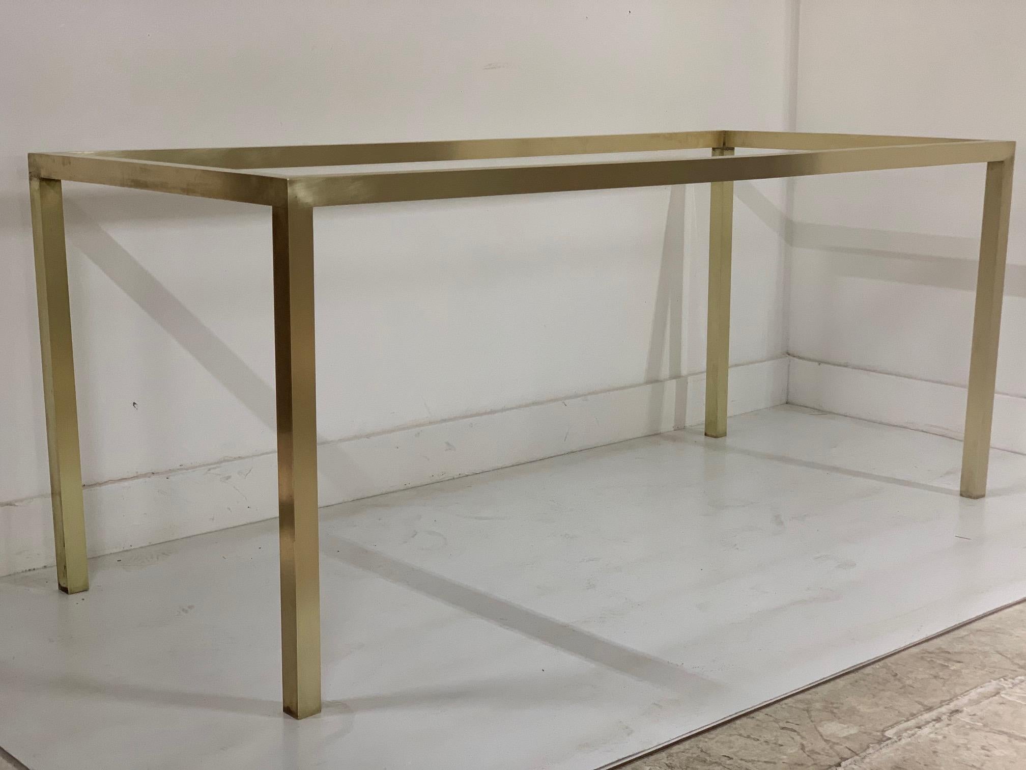 Mid-Century Modern brass table with glass top. The table base is brass with a 68”W glass top.