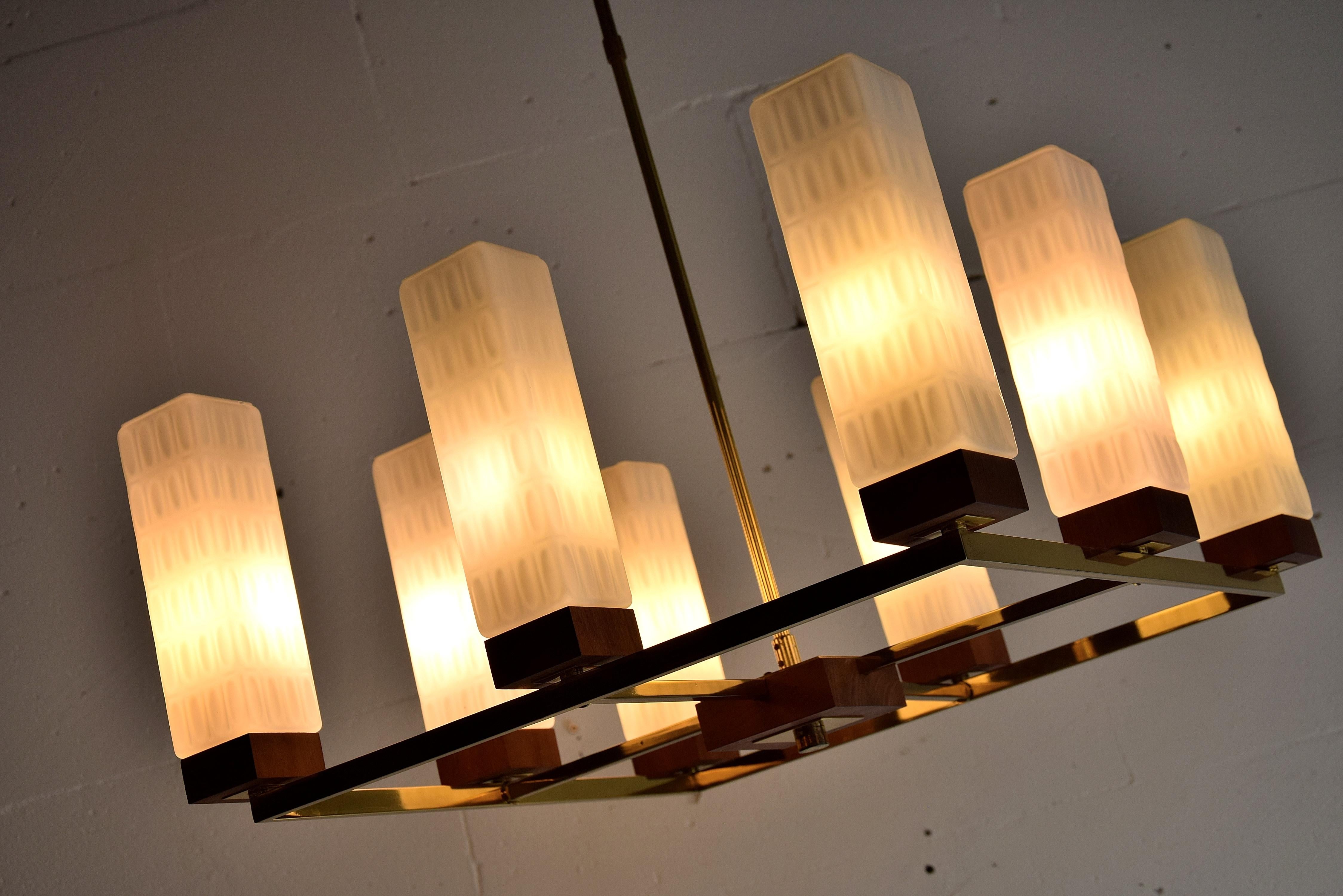 Sophisticated, elegant and stylish Mid-Century Modern brass, Teak and milk glass chandelier made by Primat Kaiser in the 1960s.
The chandelier is in fantastic condition and the chalises diffuse the light in a pleasant way. Two of the milk glass