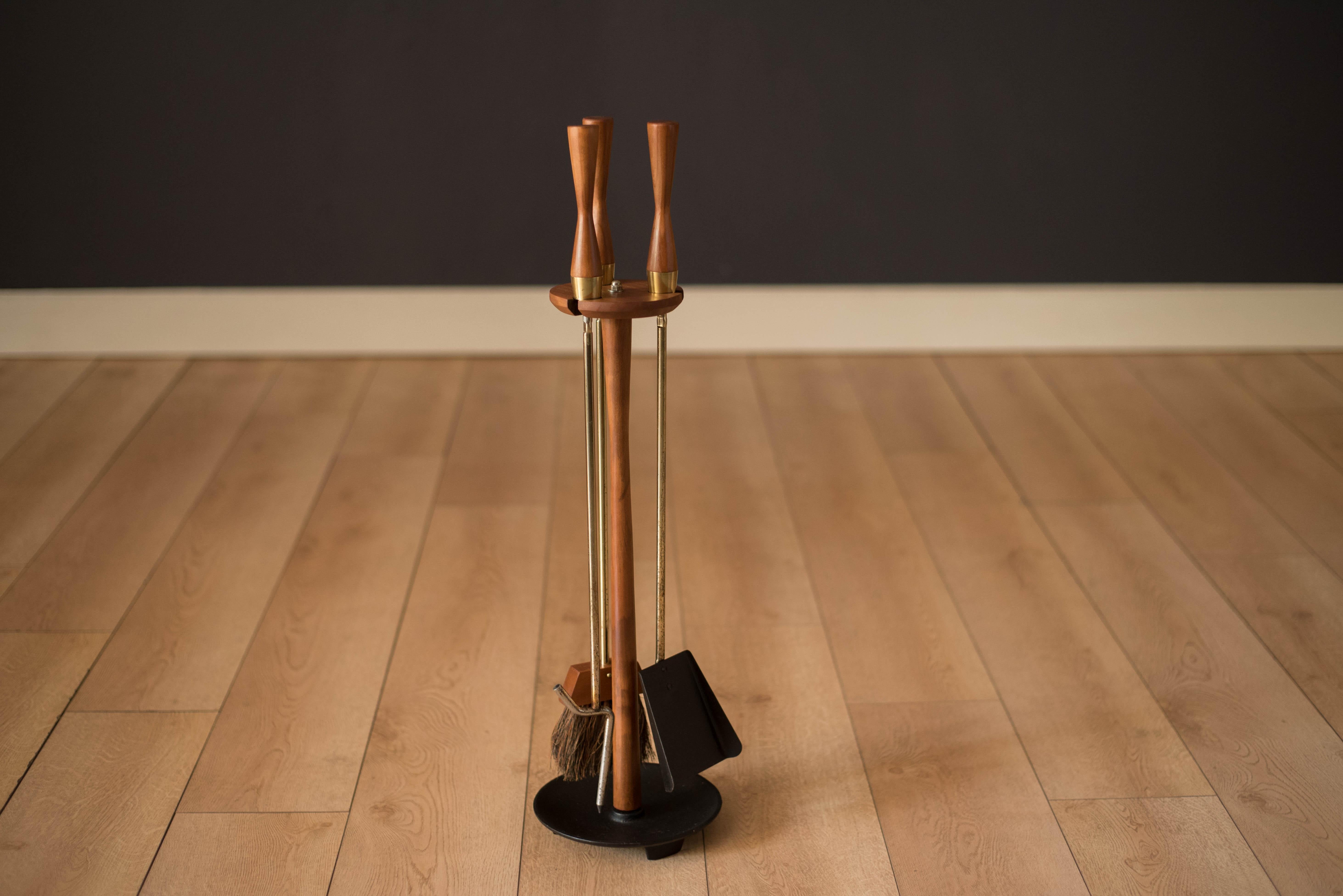 Vintage 3-piece fireplace tool set and floor stand, circa 1960s. This set is made in brass with sculpted wood handles. Includes poker, shovel, brush, and weighted cast iron floor stand.