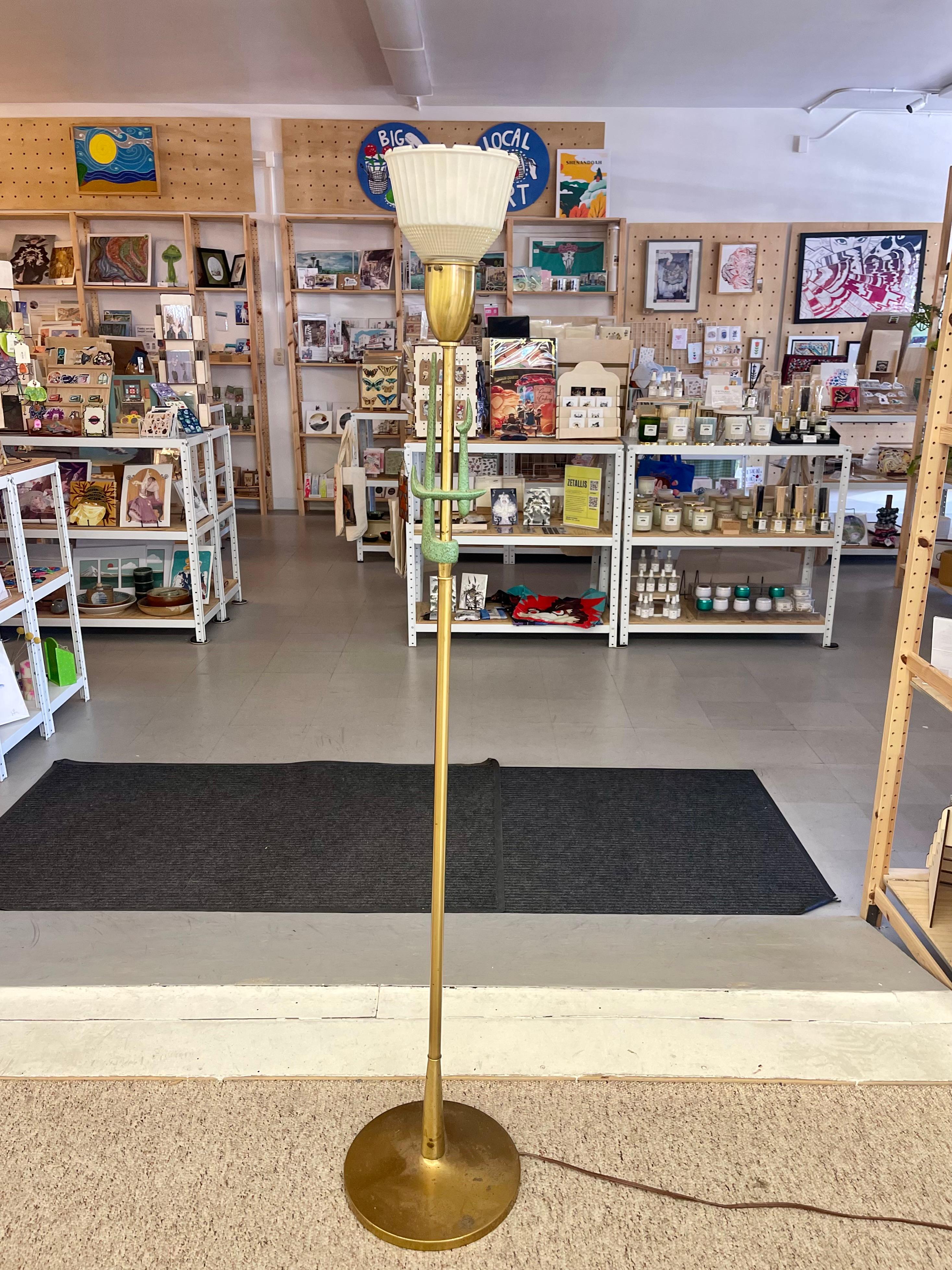 Striking mid-century torchiere floor lamp in brass with a sculptural design element in cast patinated metal. The tall, slender column supports an upward-facing, fluted glass shade that softly diffuses light. A central decorative feature-three