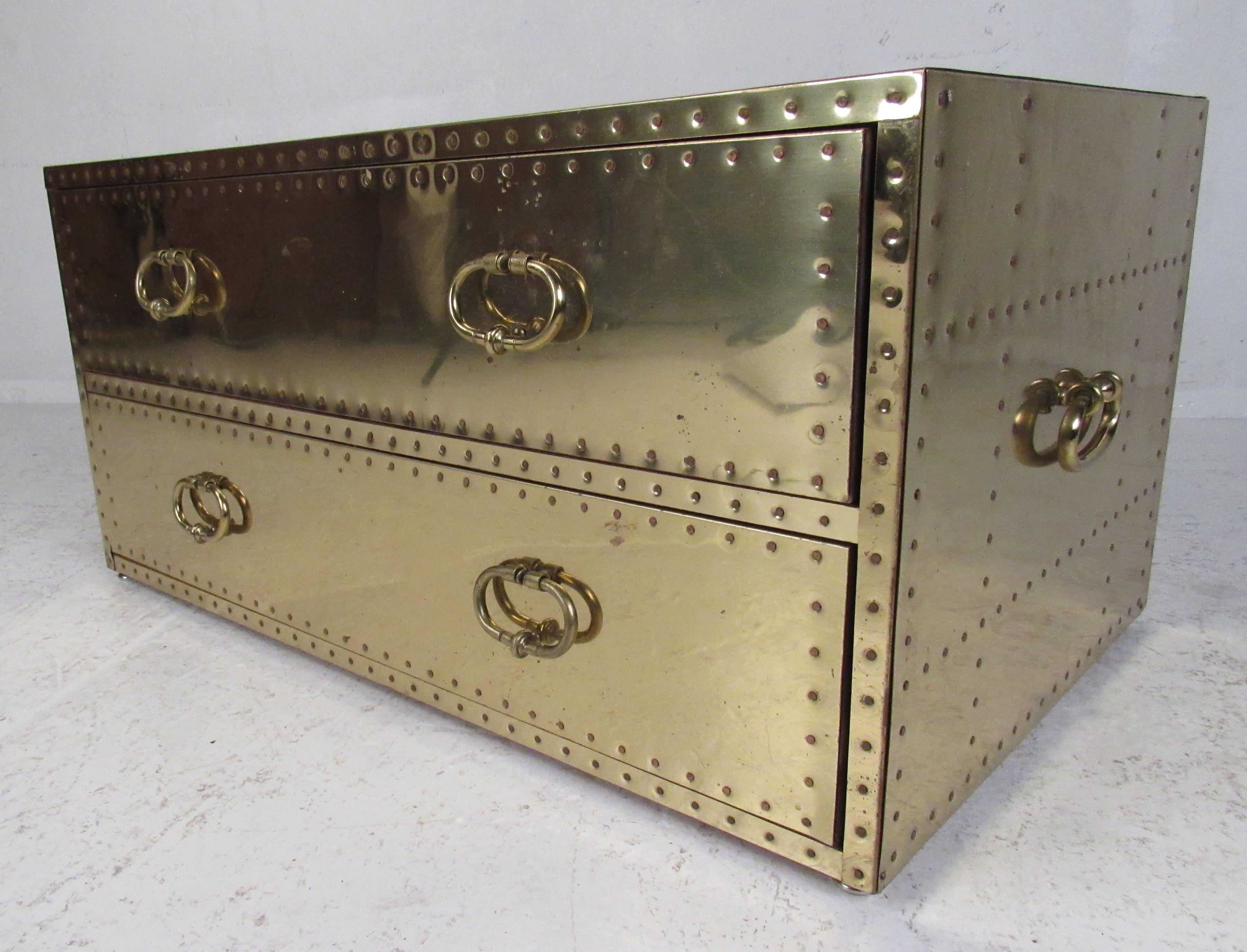 This elegant 1960s brass clad chest with copper tacks has two large drawers ensuring ample storage space. An original Sarreid Ltd label inside the top drawer and wonderful patina adds to the allure. This versatile Spanish midcentury chest or coffee