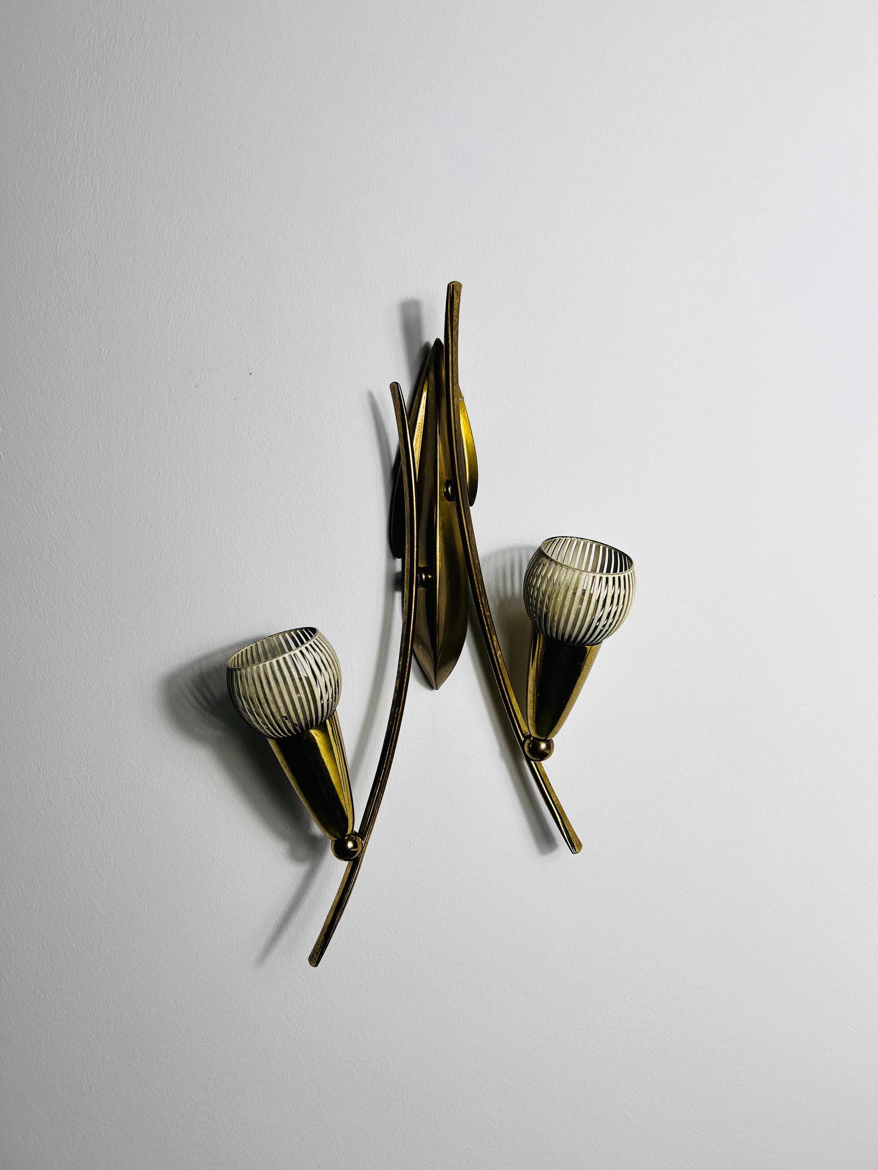 Questa splendida lampada da parete, realizzata in Italia negli anni '60, è interamente in ottone massiccio e presenta un design elegante e angolare influenzato dall'estetica Bauhaus.

L'uso della struttura in ottone crea un look sofisticato ma senza