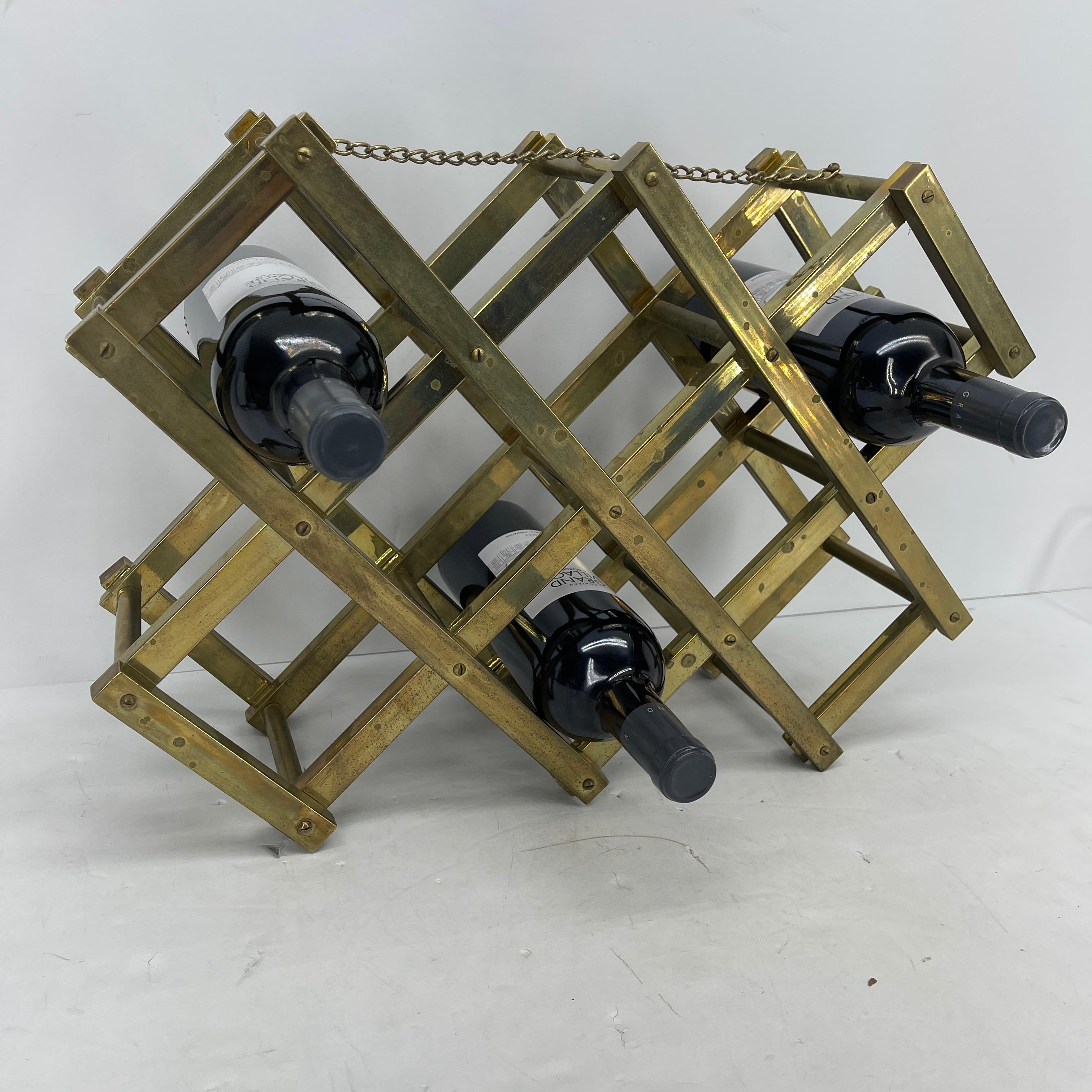 Mid-Century Modern brass foldable wine rack with decorative chain along top. The rack holds 10 bottles of wine. The wine rack has an aged brass patina. Fully collapsible, this sturdy wine rack can easily be transported to any on the go party or