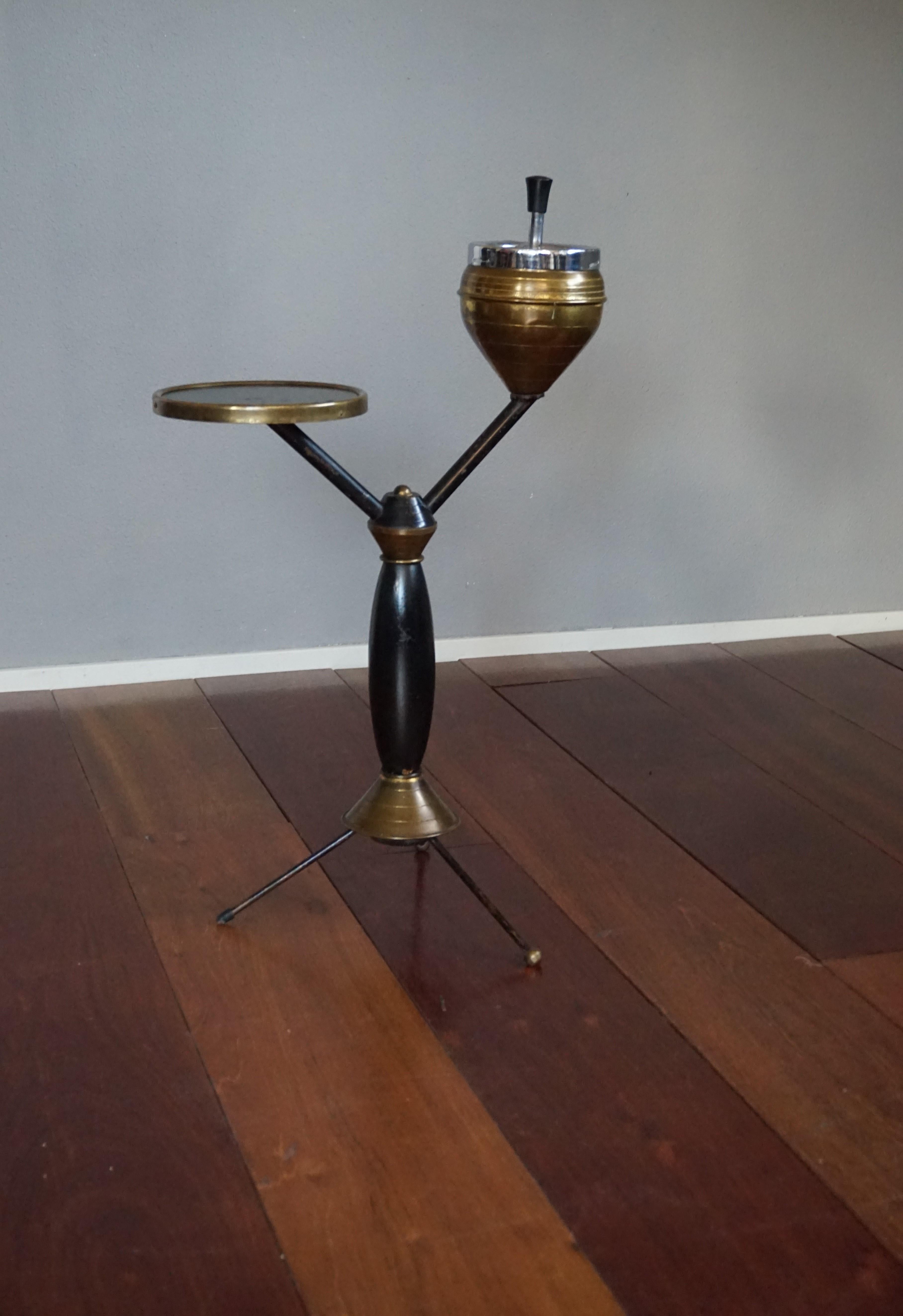 Rare and coolest design smoking stand.

Yes, one of the brass balls on the tripod base has been replaced by a black rubber 'stud' and yes there is some wear, but where on earth are you ever going to find another one of these beautifully designed,