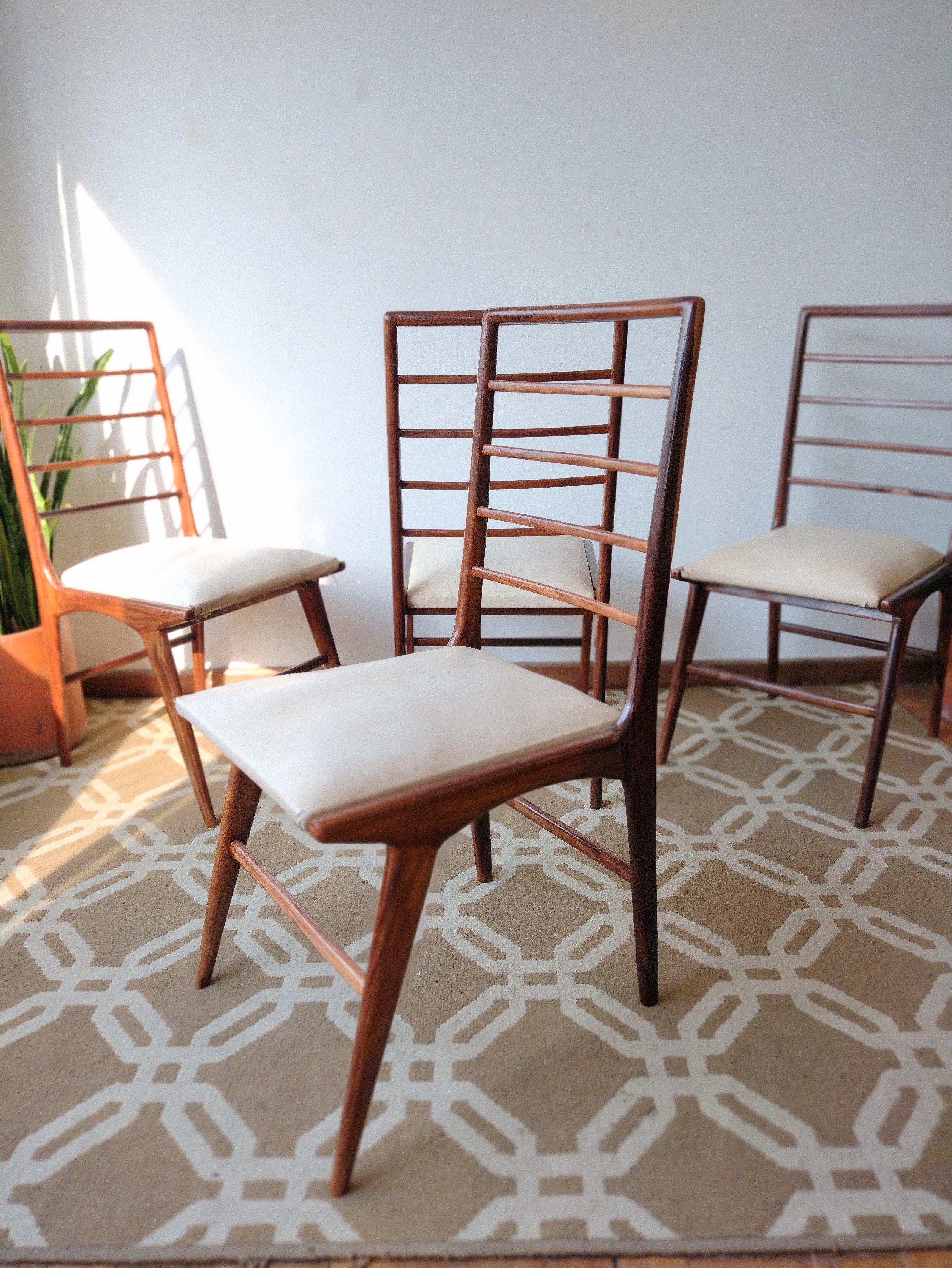 Set of 4 Mid-Century Modern Brazilian chairs with structure in noble solid wood (recently refinished) and a seat with springs covered with original offwhite courvin (faux leather). Firm structure. Overall great condition with only minor age