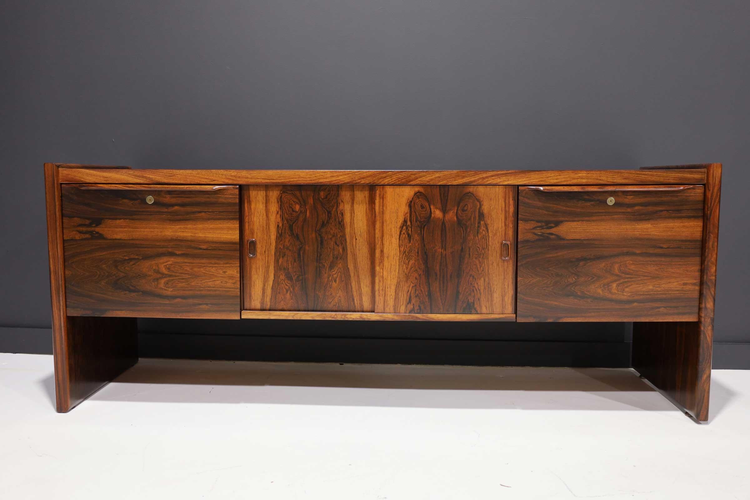 Gorgeous credenza with highly figured Brazilian rosewood veneer. Credenza features two drawers with room for legal or letter files and two sliding door with storage compartments. Credenza is finished in back for floating in room if needed.