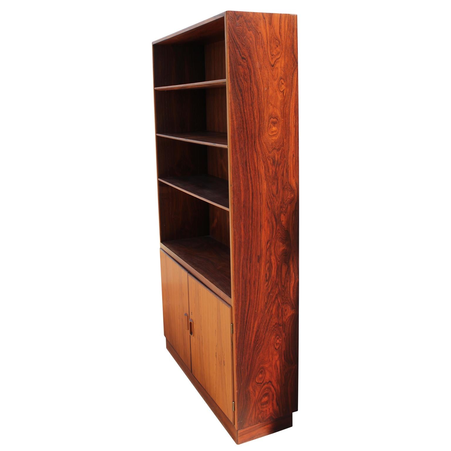 A Mid-Century Modern Danish bookcase made from gorgeous Brazilian rosewood featuring four shelves and cabinet space below that opens to reveal a single shelf by Søborg.