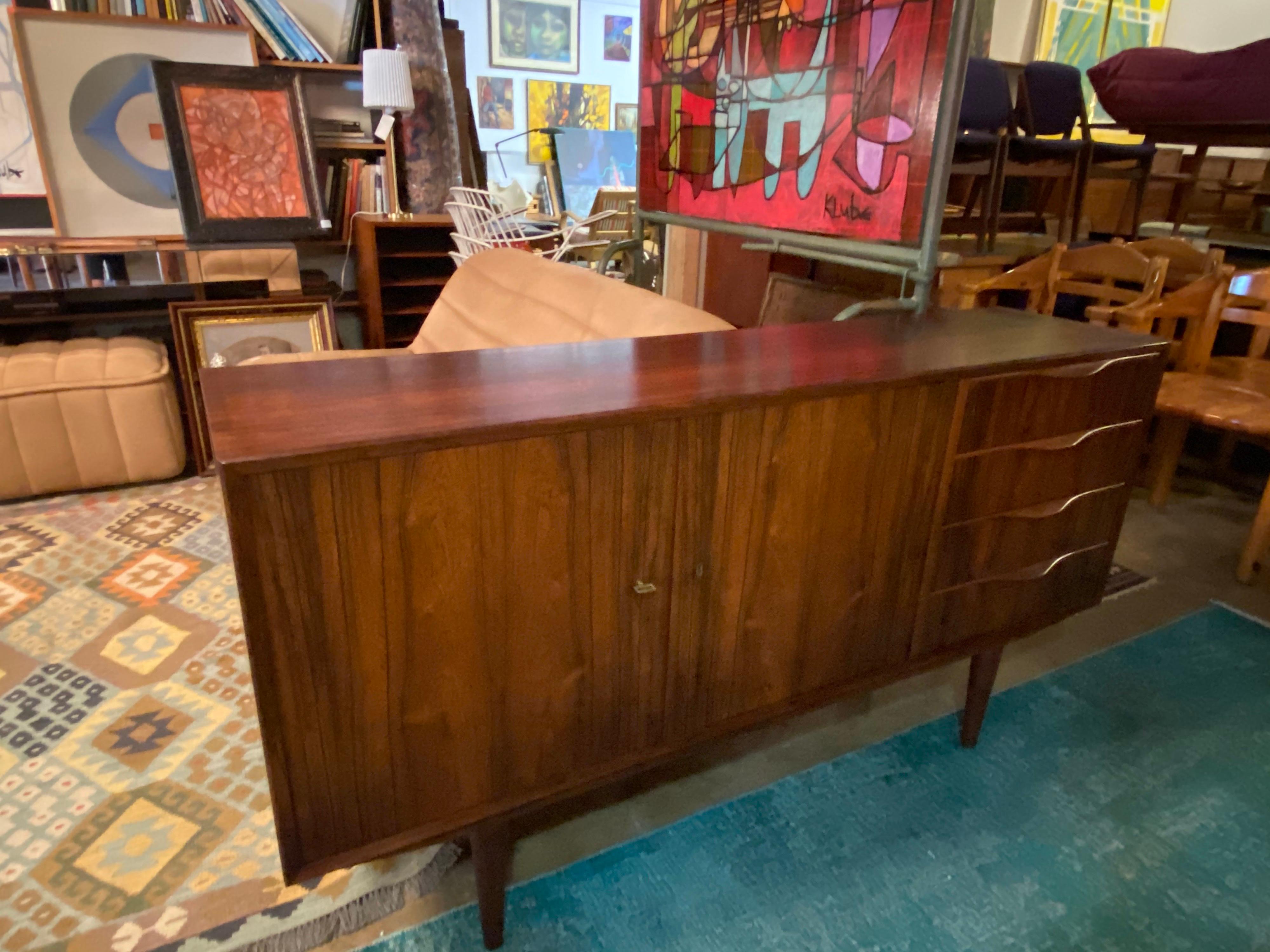 Beautiful Mid-Century Modern Brazillian rosewood credenza sideboard features four drawers with sculpted handles and a total of four shelves for storing. This small mid-century credenza is perfect for small and large spaces and is in great overall