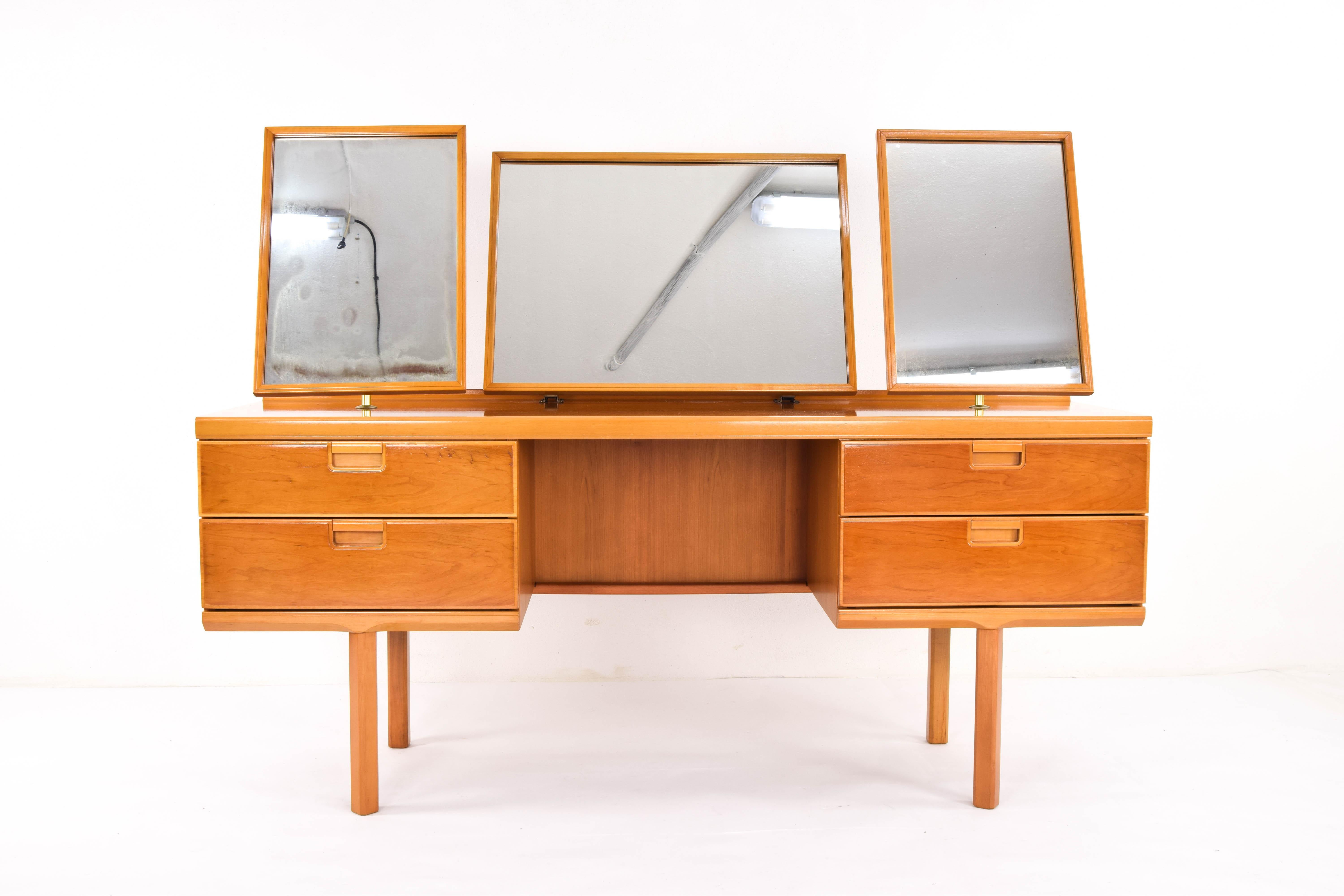 British beechwood dressing table from the late 1960s.
Composed of three mirrors with brass steel foot, four drawers and octagonal legs. Their mirrors have their own patina of the years, to a greater extent the one to the left of the images.