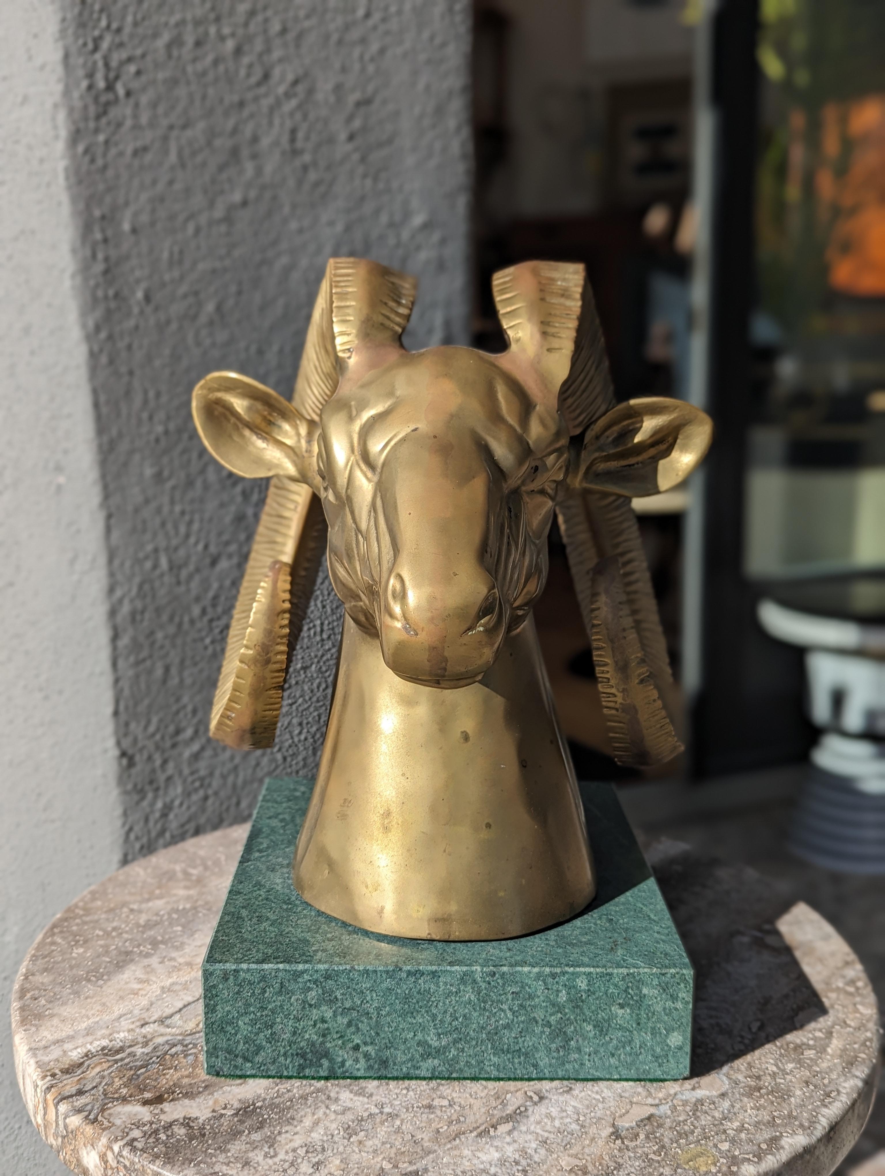 Die Mid-Century Modern Brass Ram Sculpture ist aus massivem Messing gefertigt und steht auf einem Sockel aus poliertem grünem Marmor. Sie verkörpert die rohe Kraft und den ungezähmten Geist des Dickhornbocks, verbunden mit dem eleganten Stil einer