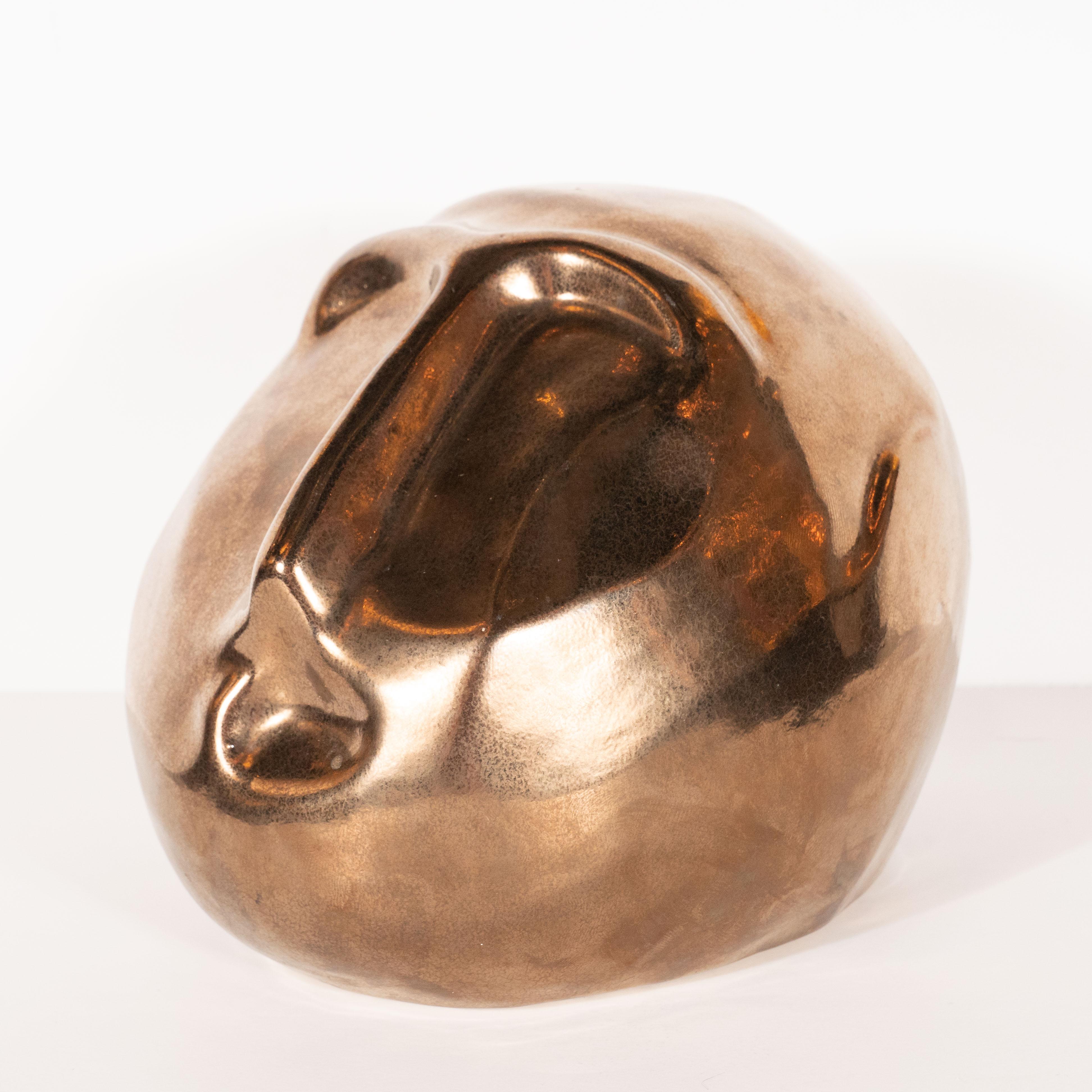 This sophisticated figurative sculpture was realized by the esteemed artist Jaru, circa 1970. It presents a stylized and abstracted male head in bronze glazed ceramic, recalling the work of Constantin Brancusi. Drawing upon Brancusi's influences