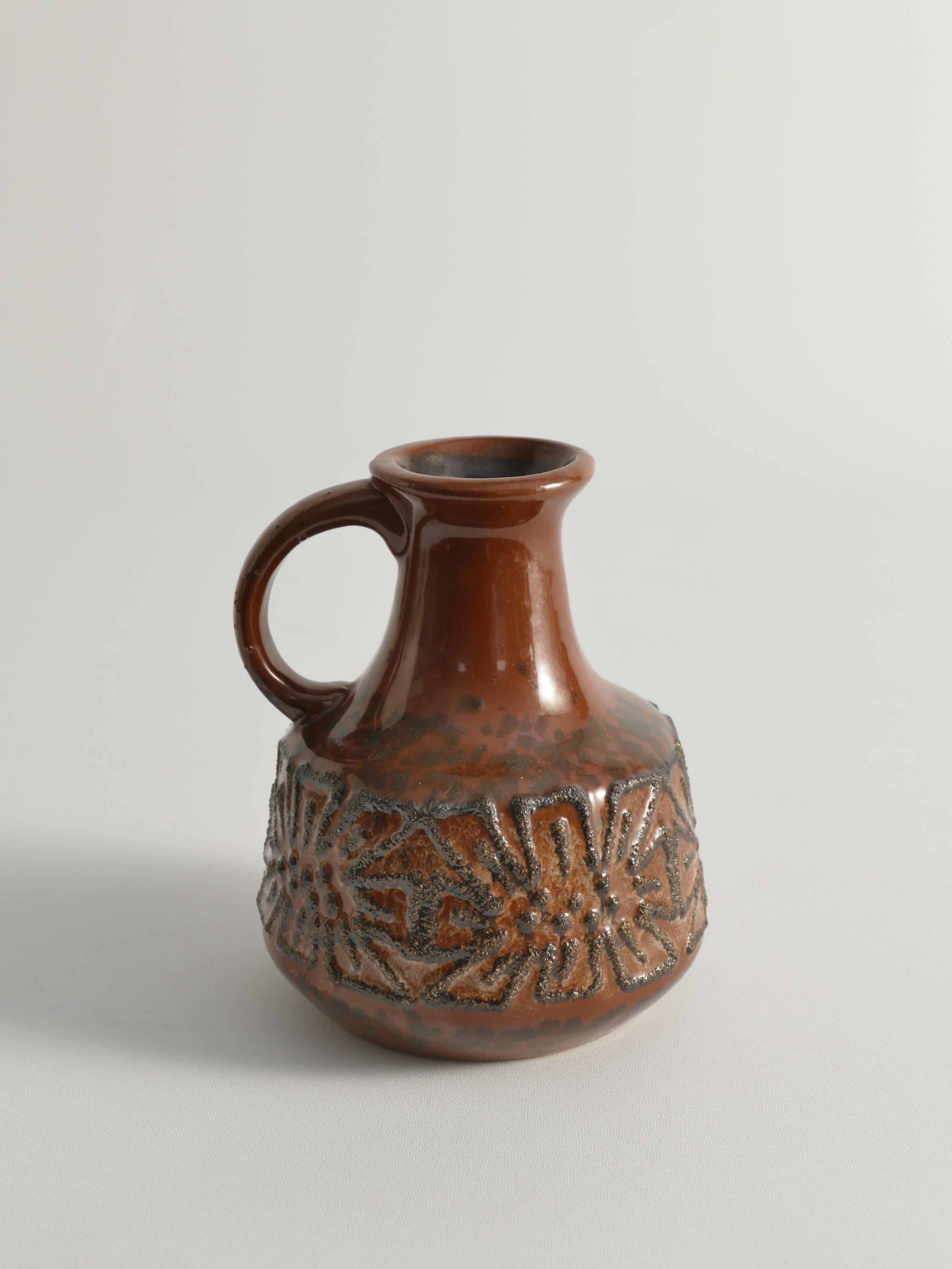 Questa brocca in ceramica, proveniente dalla Germania dell'Est degli anni '70, è un esempio di design di metà secolo. Realizzato da VEB Haldensleben negli anni '60, questo pezzo presenta uno splendido smalto marrone scuro e cannella. Il vaso,