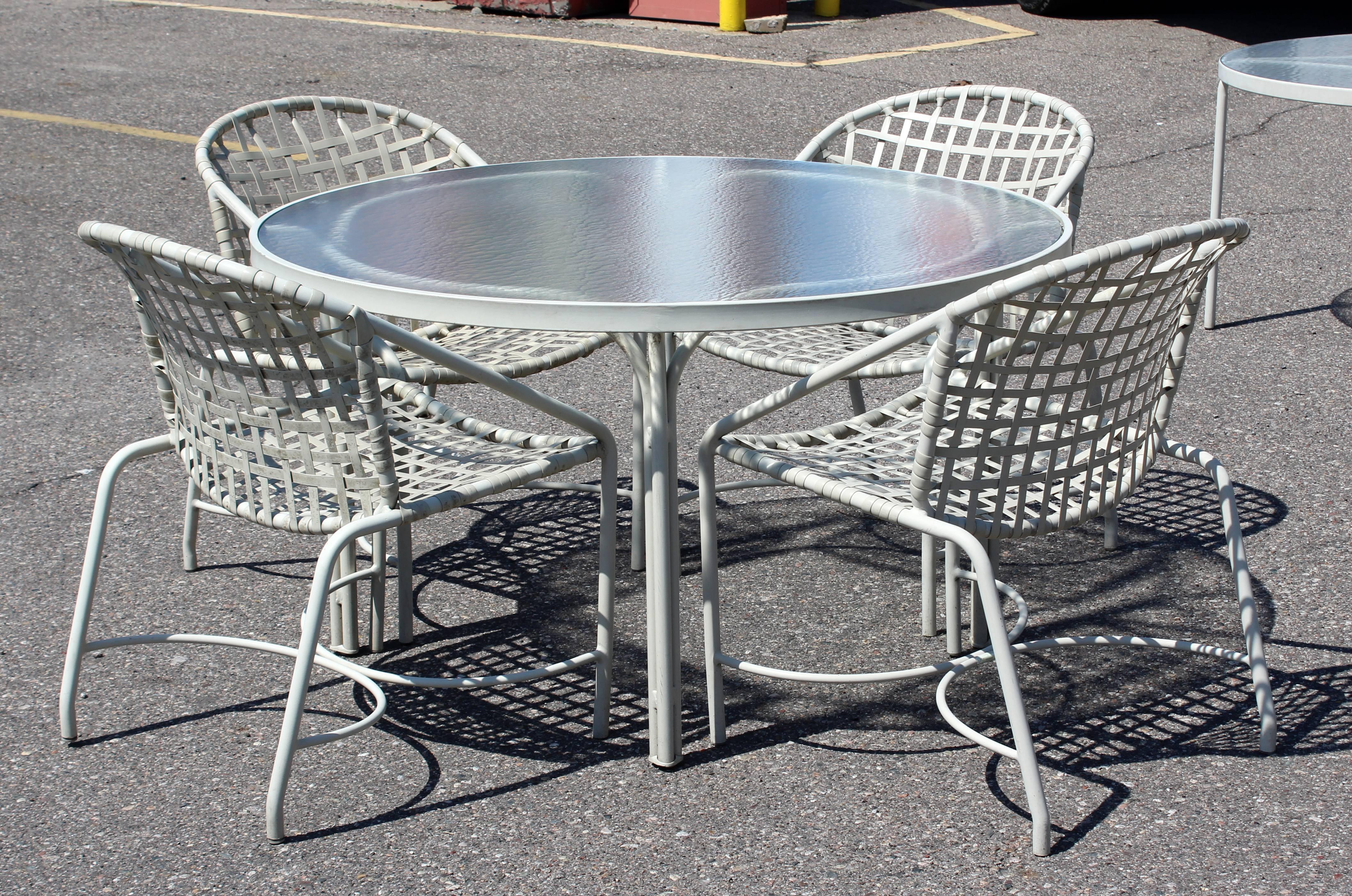 For your consideration is an outdoor patio dining set, including a table with a glass top and four chairs, by Brown Jordan the Kantan series, circa the 1960s. In excellent condition with a very minor chip in the glass. The dimensions of the table