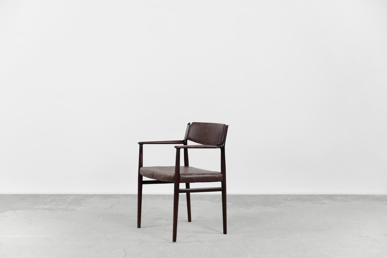 Dieser modernistische Stuhl wurde in den 1960er Jahren von dem weltberühmten dänischen Designer Arne Vodder entworfen. Das organisch geformte Gestell des Stuhls ist aus Massivholz in einem edlen, braunen Farbton gefertigt. Der Sitz und die