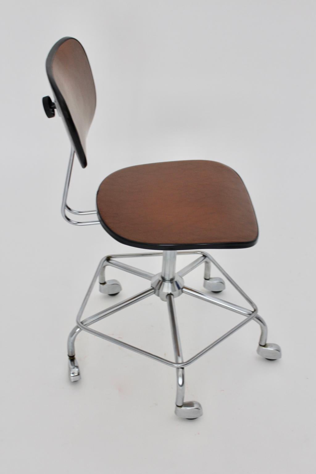 Mid Century Modern adjustable and swiveling vintage desk chair in brown faux leather attributed to Egon Eiermann, 1950s Germany.
The seat and back made of plywood were covered with brown faux leather. Furthermore the desk chair shows a chrome-plated
