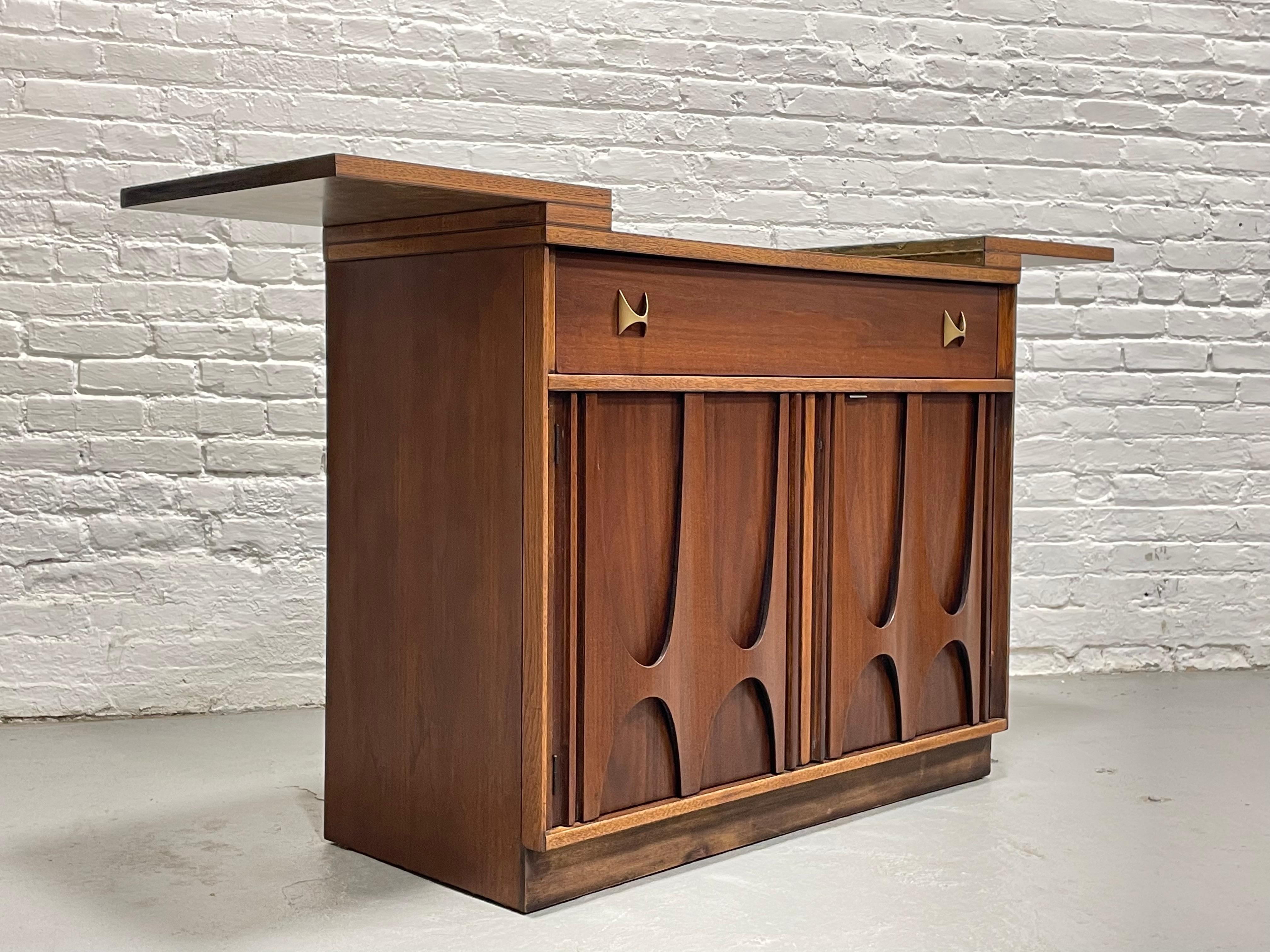 Mid Century Modern Broyhill Brasilia Liquor Cabinet / Bar, c. 1960's. This is a magnificent and rare bar cabinet from the much beloved and voraciously collected Brasilia collection. From the distinctive elongated, inverted sculpted arches to the