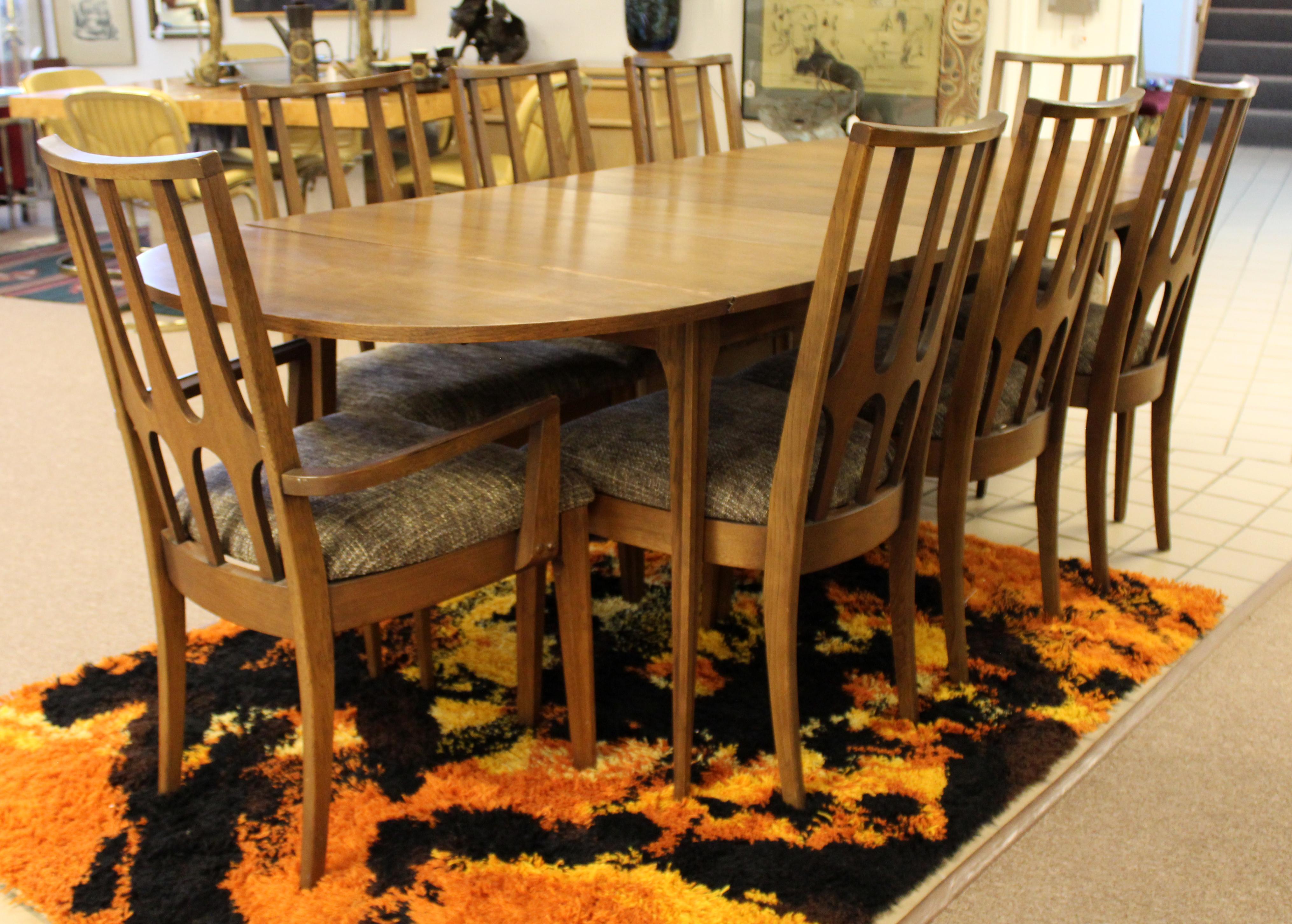 For your consideration is a wonderful, drop leaf dining table and set of eight chairs, by Broyhill Brasilia, circa the 1960s. In excellent vintage condition. Chairs just came back from being professionally reupholstered. The dimensions of the table