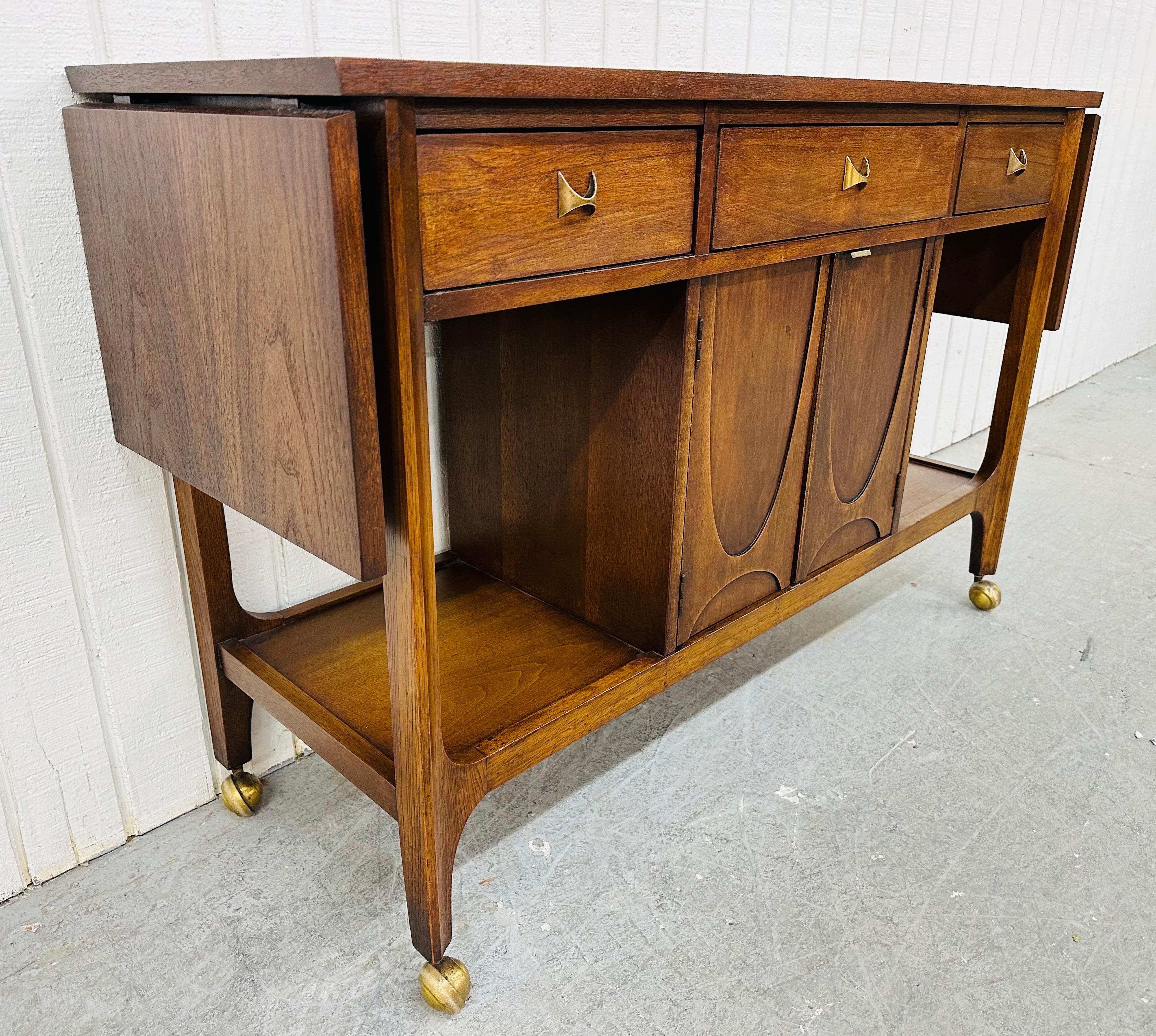 This listing is for a Mid-Century Modern Broyhill Brasilia Walnut Bar Cart. Featuring a straight line drop leaf design that extends the length to 70.5” L, original blue tile insert top, three drawers with original brass pulls, two doors that open up