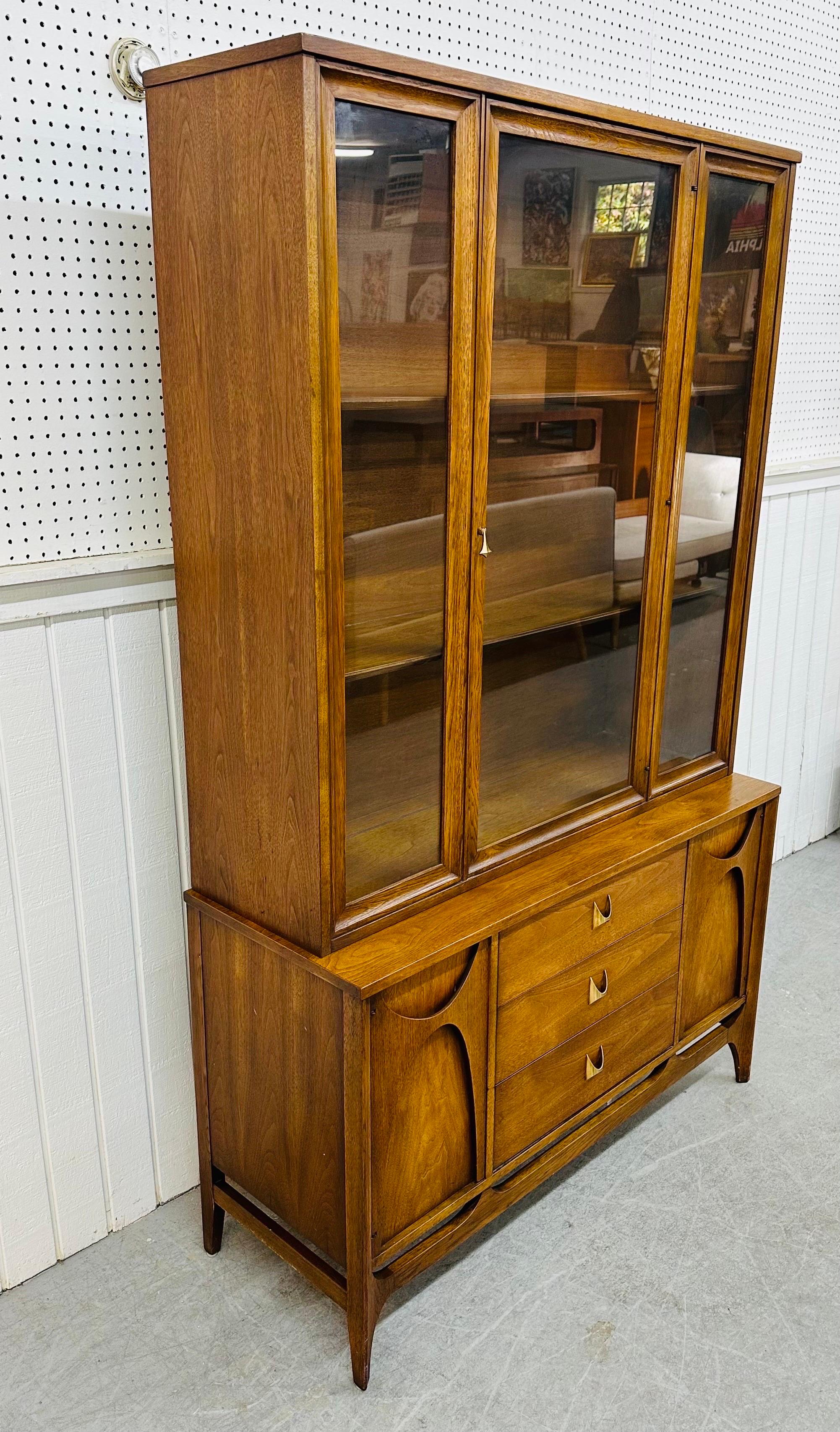 This listing is for a Mid-Century Modern Broyhill Brasilia Walnut China Cabinet. Featuring a straight line design, removable glass top, single door that opens up to storage space, a base that has two doors with the iconic sculpted Brasilia design,