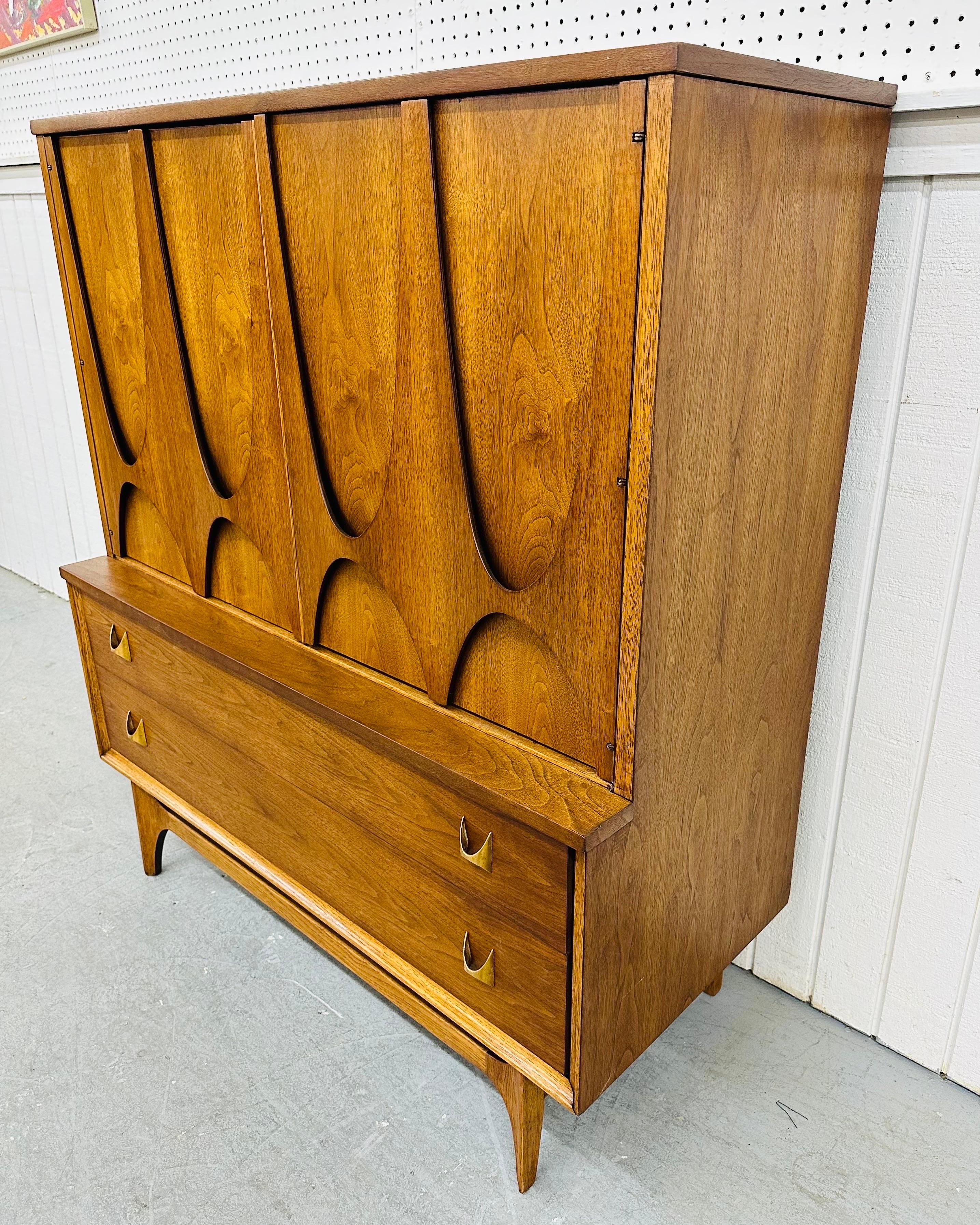 This listing is for a Mid-Century Modern Broyhill Brasilia Walnut High Chest. Featuring a straight line design, two large doors with the iconic Brasilia sculpted pulls, four small drawers with storage space on the left side, two largest drawers at