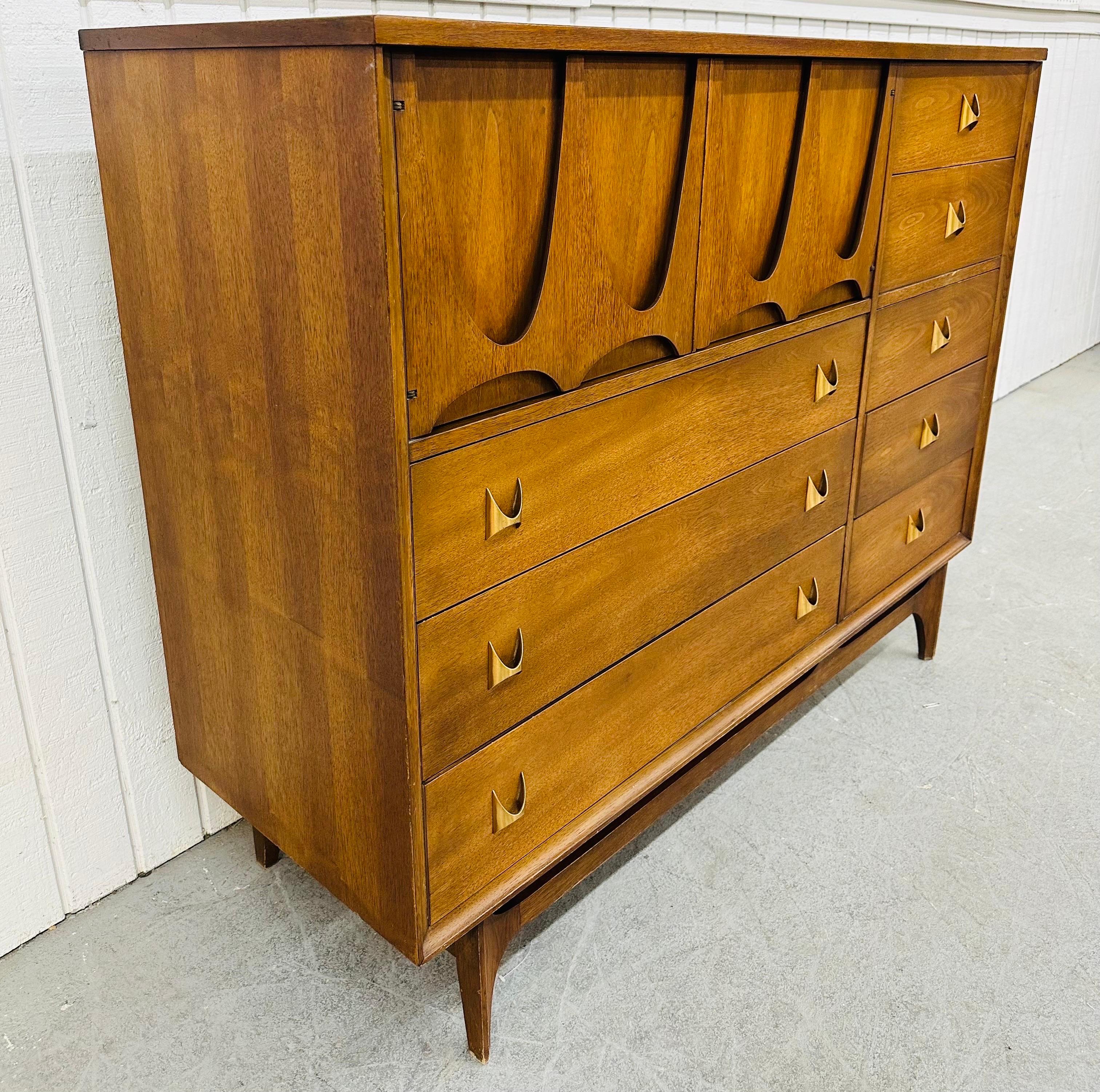 This listing is for a Mid-Century Modern Broyhill Brasilia Walnut Magna Chest. Featuring a straight line design, two doors with sculpted Brasilia pulls that open up to storage space, three larger drawers underneath, five small drawers on the right