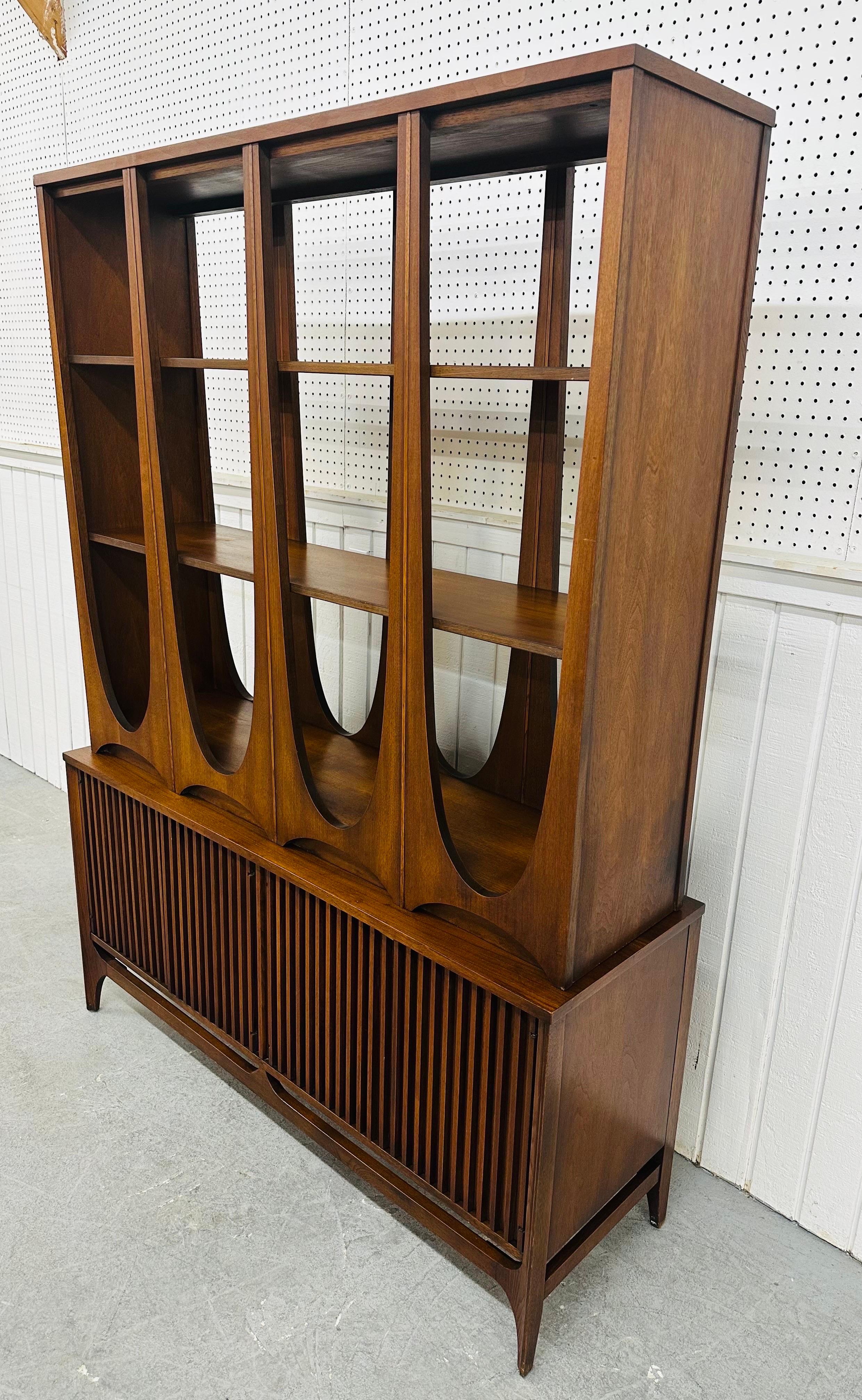 This listing is for a Mid-Century Modern Broyhill Brasilia Walnut Room Divider. This rare and iconic piece from the Broyhill Brasilia collection features a two-piece design finished on both sides in a beautiful walnut stain. The sculpted top sits on