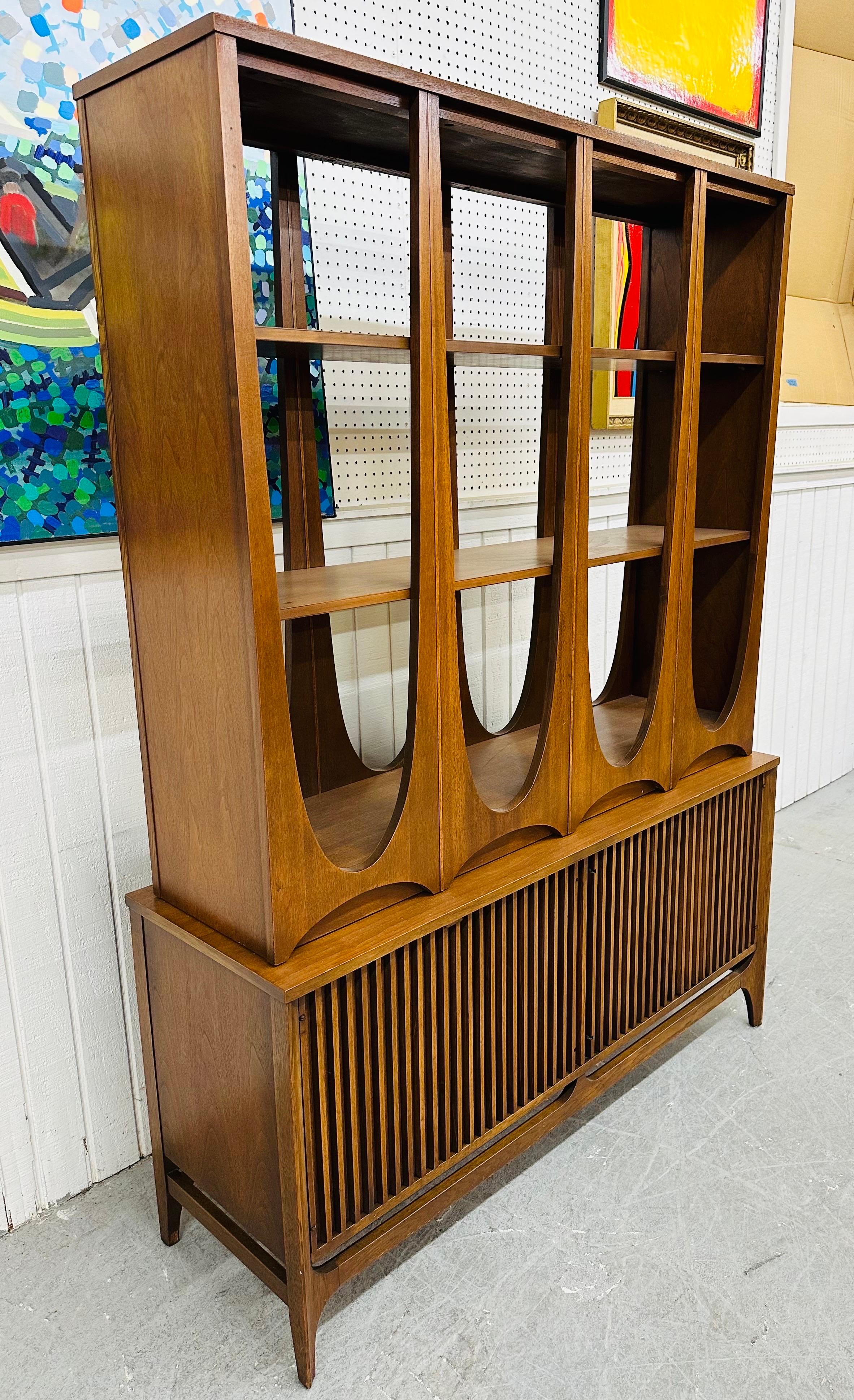 This listing is for a rare Mid-Century Modern Broyhill Brasilia Walnut Room Divider. Featuring a straight line two piece design, sculpted shelving top, reeded doors on the base that open up to drawers/shelving space, modern legs, mirrored finished