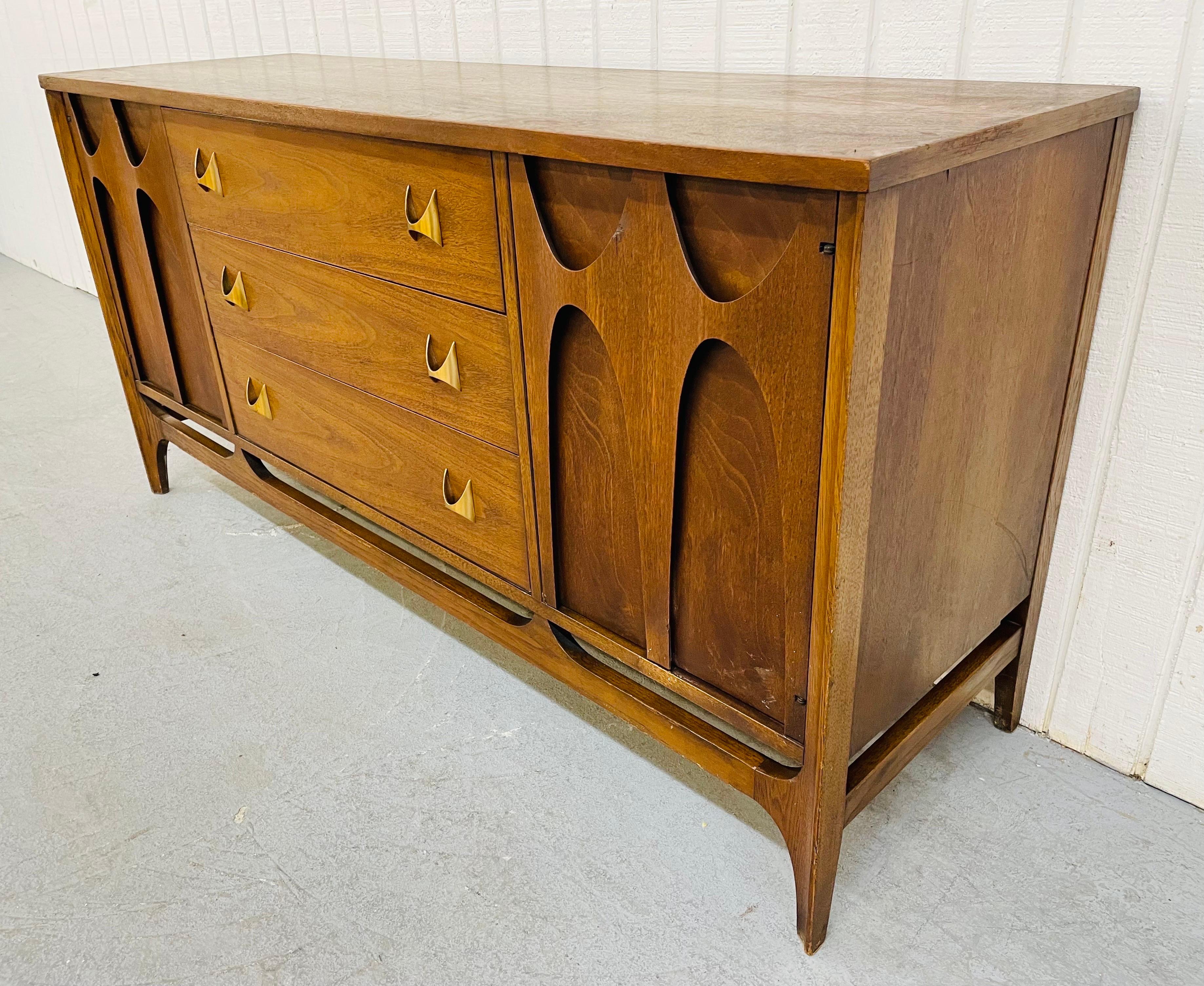 This listing is for a Mid-Century Modern Broyhill Brasilia walnut server. Featuring two doors with the iconic Brasilia curved wood arches that open up to storage space, three center drawers with the iconic Brasilia brass hardware, and a beautiful
