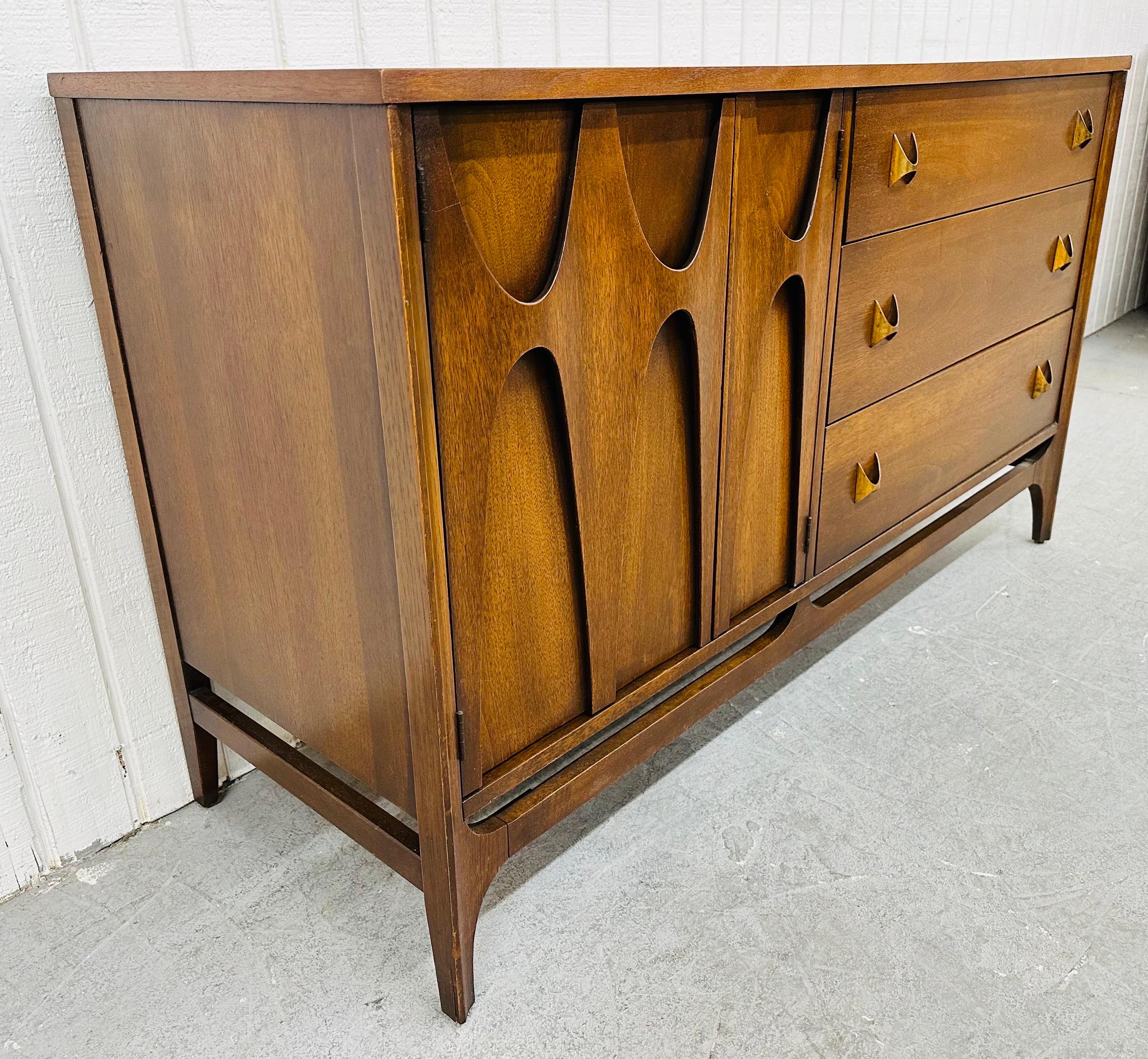 This listing is for a Mid-Century Modern Broyhill Brasilia Walnut Server. Featuring a straight line design, sculpted doors on the left that open up to storage space, three drawers on the right, original brass Brasilia pulls, and a beautiful walnut