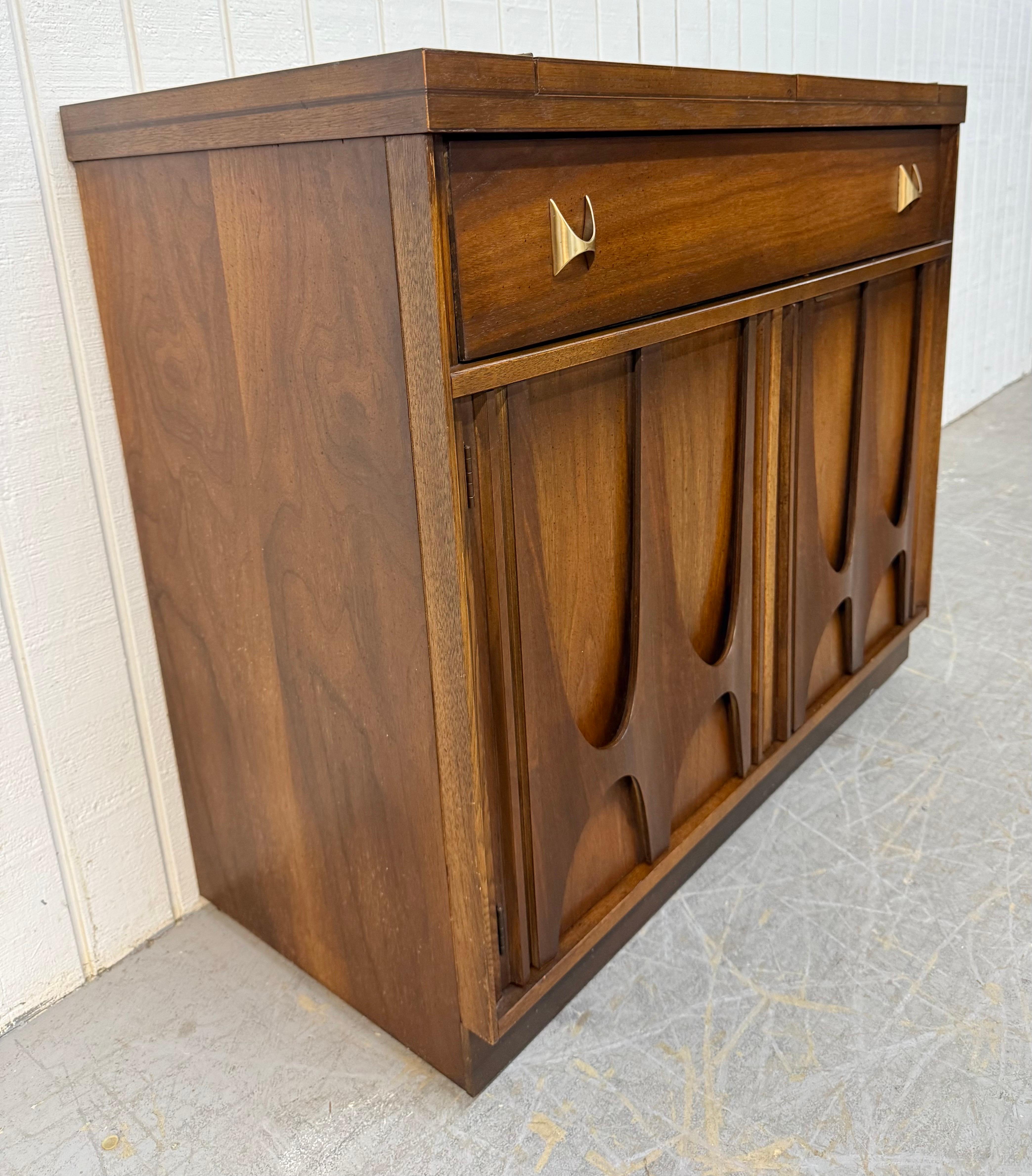 This listing is for a Mid-Century Broyhill Brasilia Walnut Serving Cart. Featuring a straight line , rectangular burled laminated flip-top that expands to 59.5