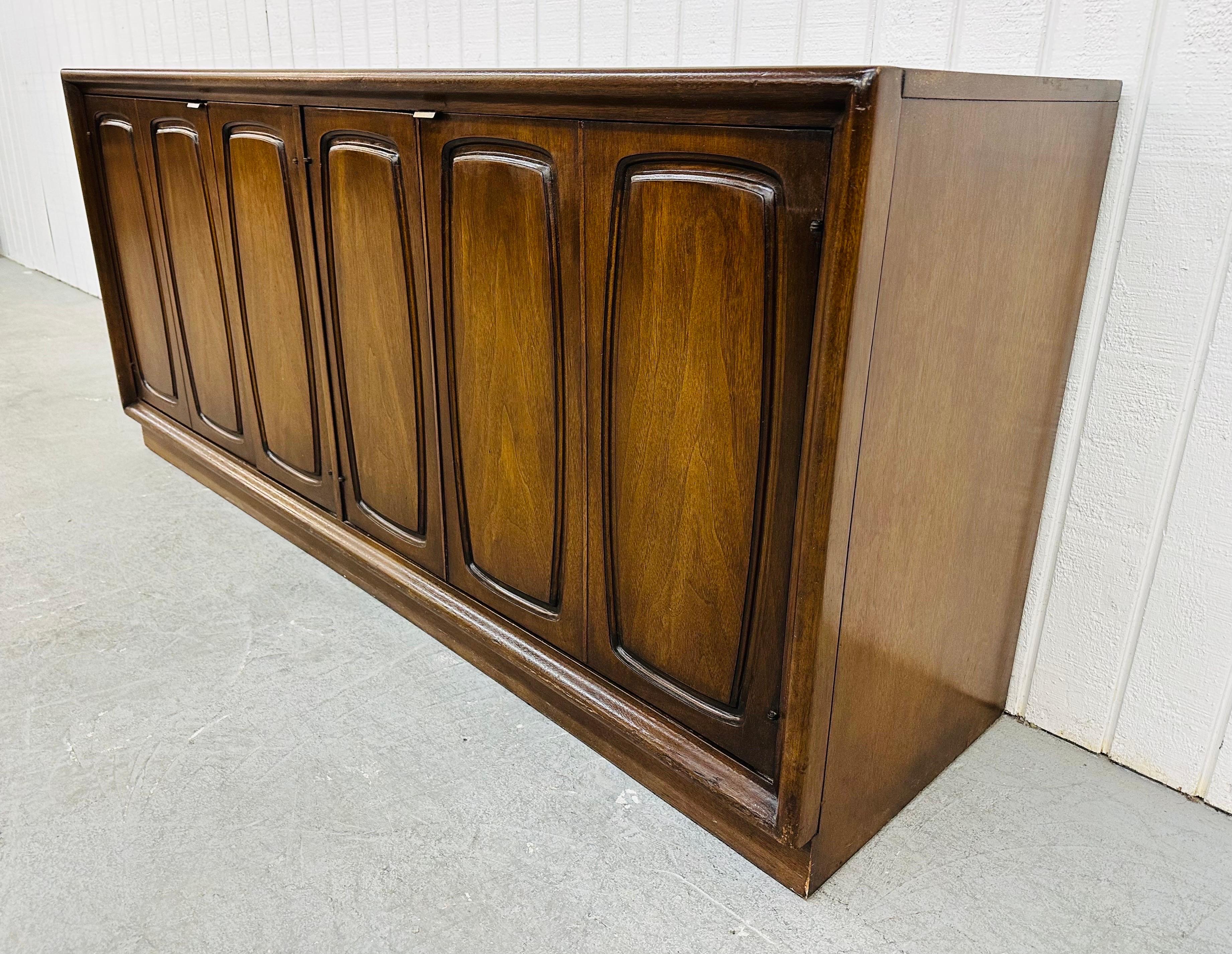 This listing is for a Mid-Century Modern Broyhill Emphasis Walnut Sideboard. Featuring a straight line design, two doors on the left that open up to storage space, two doors on the right that open up to three hidden drawers, a plinth base, and a