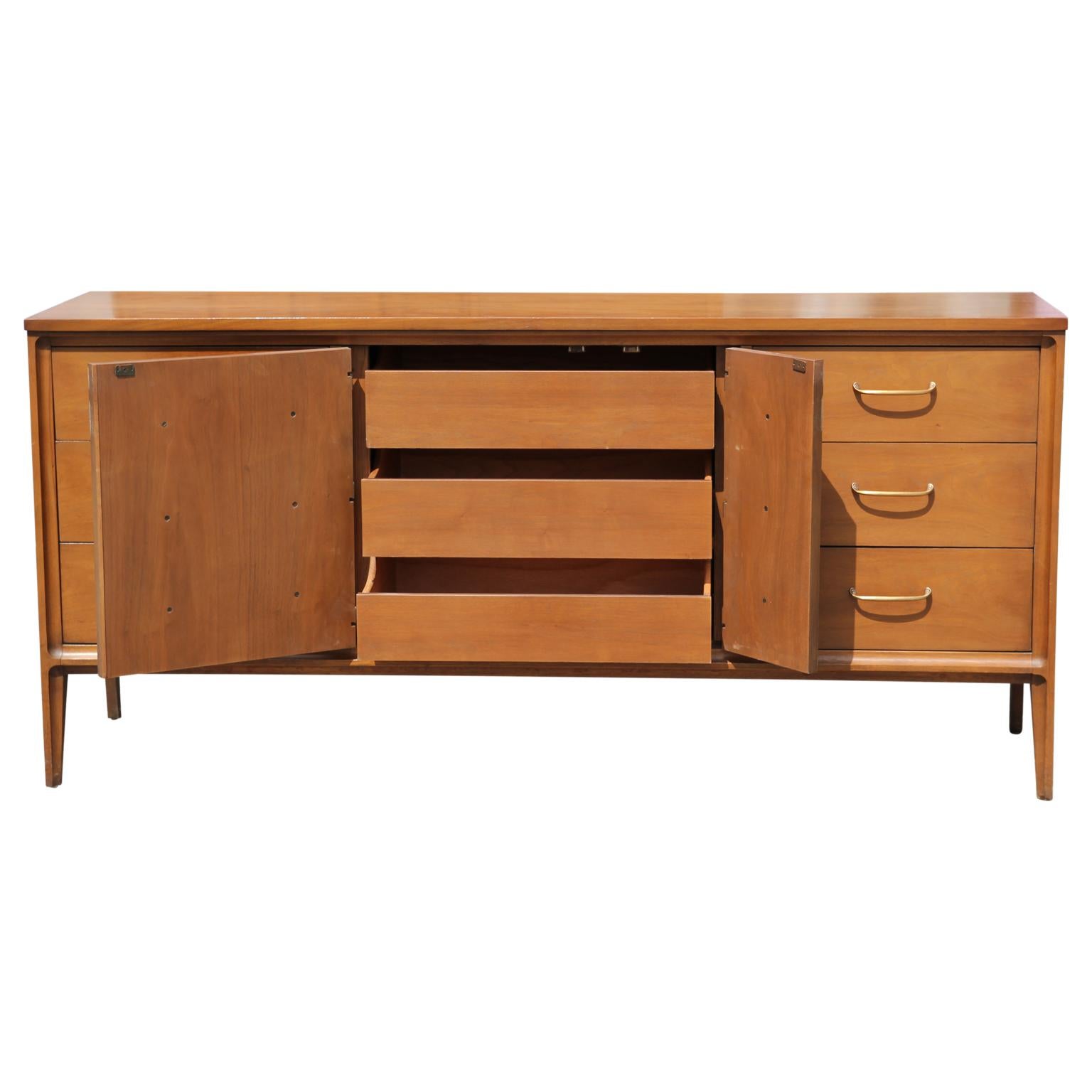 Sleek Mid-Century Modern design sideboard by Broyhill with 6 drawers and 3 more concealed drawers behind a swing out panel. The makers mark is on the inside of the top drawer. The sideboard is in great vintage condition.