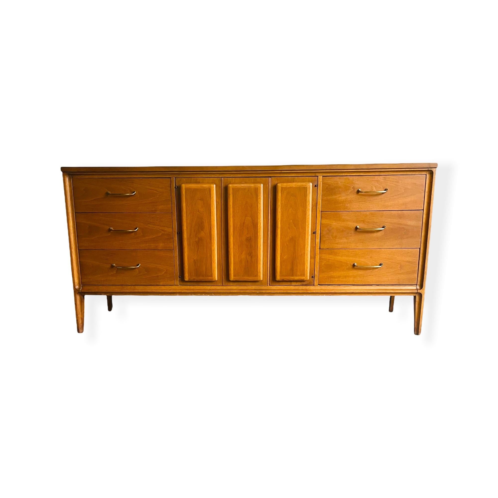 Here is a stunning Mid-Century Modern Credenza / Dresser by Broyhill Premier from their “Forward 70’s” line. This credenza is equipped with 3 drawers on each side and a double door with three drawers behind the doors, for total of 9 drawers. This