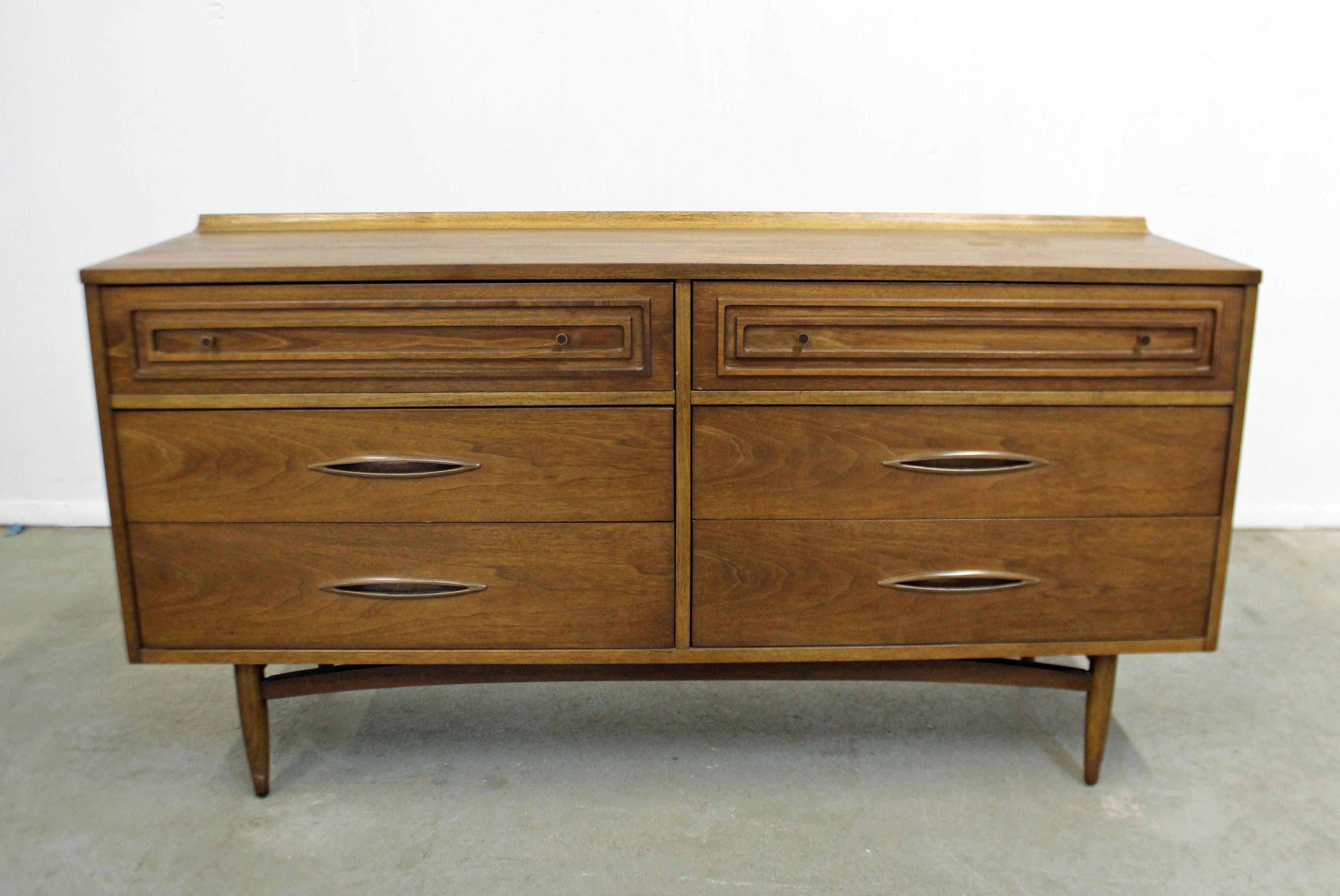 Offered is a walnut dresser/credenza made by Broyhill Premier's 'Sculptra'. Has 6 dovetailed drawers - two atop with rectangular framing on fronts and brass pulls, as well as four large bottom drawers with faux wood metal pulls. It is in excellent