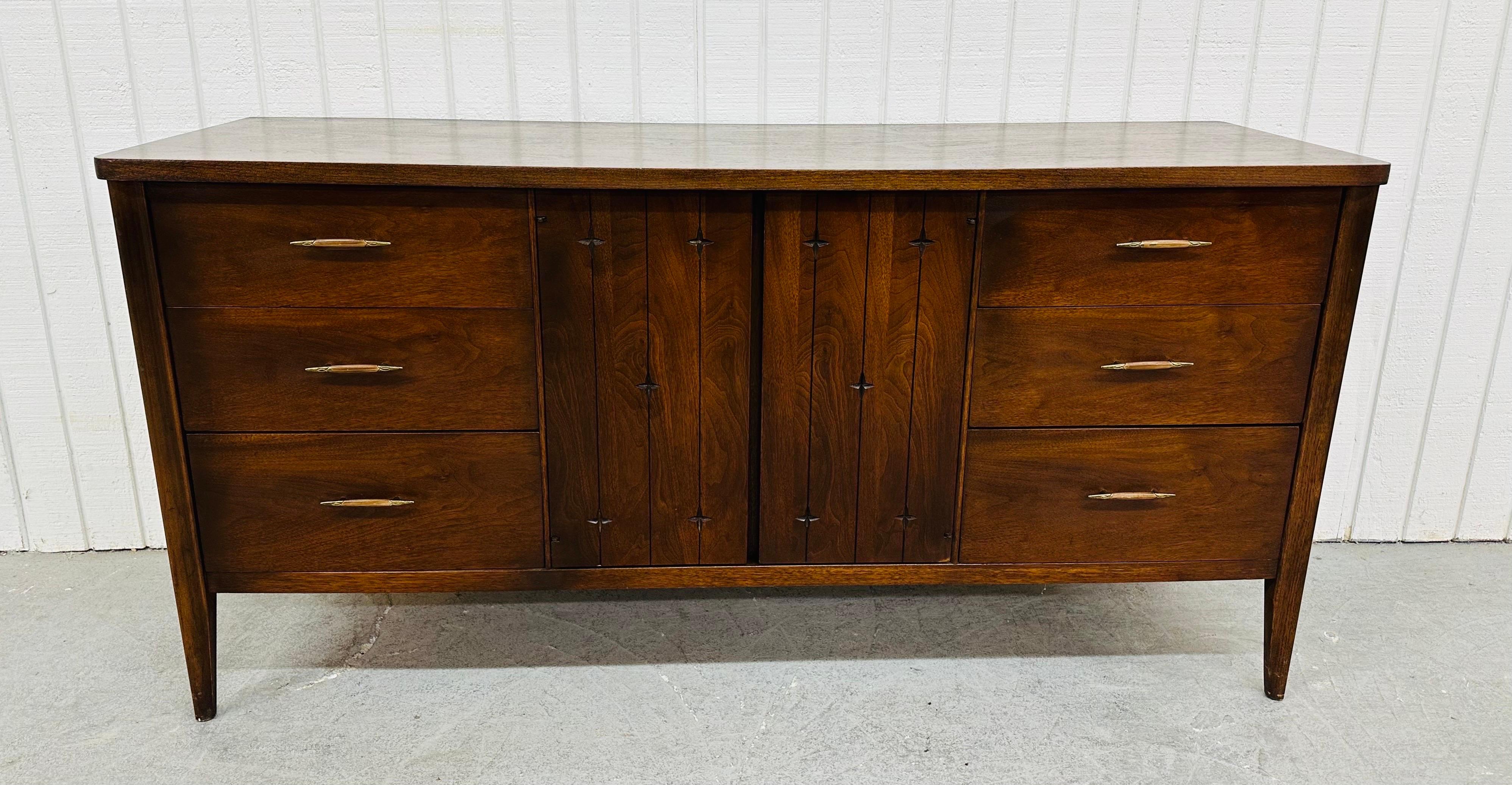 This listing is for a Mid-Century Modern Broyhill Saga Walnut Triple Dresser. Featuring a straight line design, three drawers on each side with original hardware, center doors with the iconic Saga stars carved in that open up to three hidden