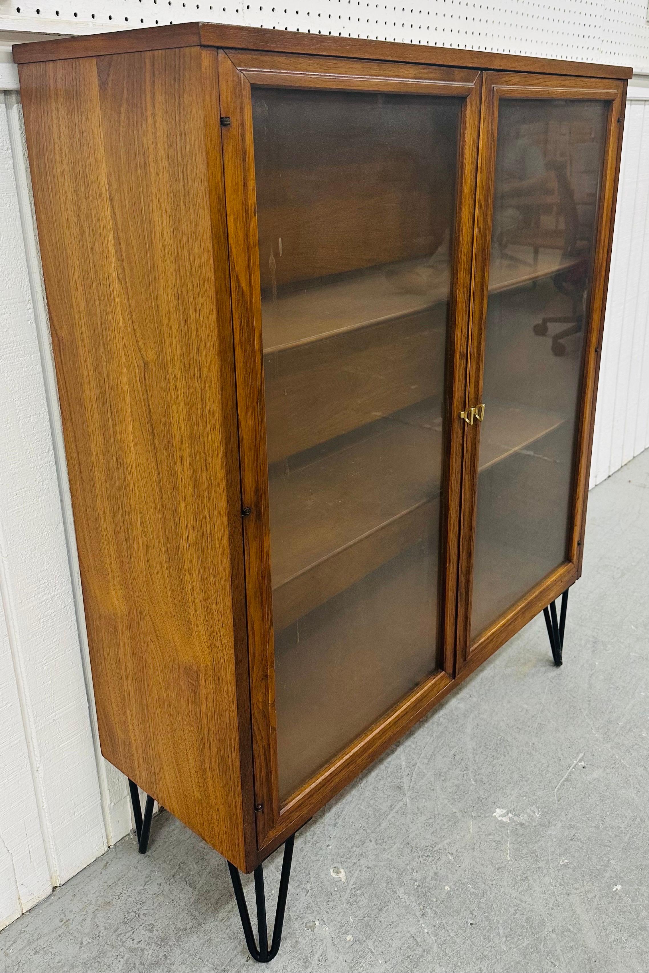 This listing is for a Mid-Century Modern Broyhill Sculptra Walnut Bookcase. Featuring a straight line design, two glass panel doors that open up to storage space, original brass hardware, and hairpin legs. This is an exceptional combination of