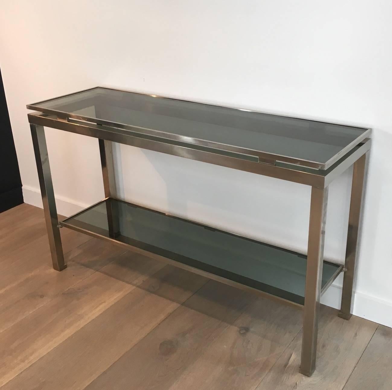 A Mid-Century Modern console made of brushed steel with blue/grey glass shelves. Designed by Guy Lefèvre for Maison Jansen, French, circa 1970s.
 
This console is currently in France, please allow 2 to 4 weeks delivery to New York. Shipping cost