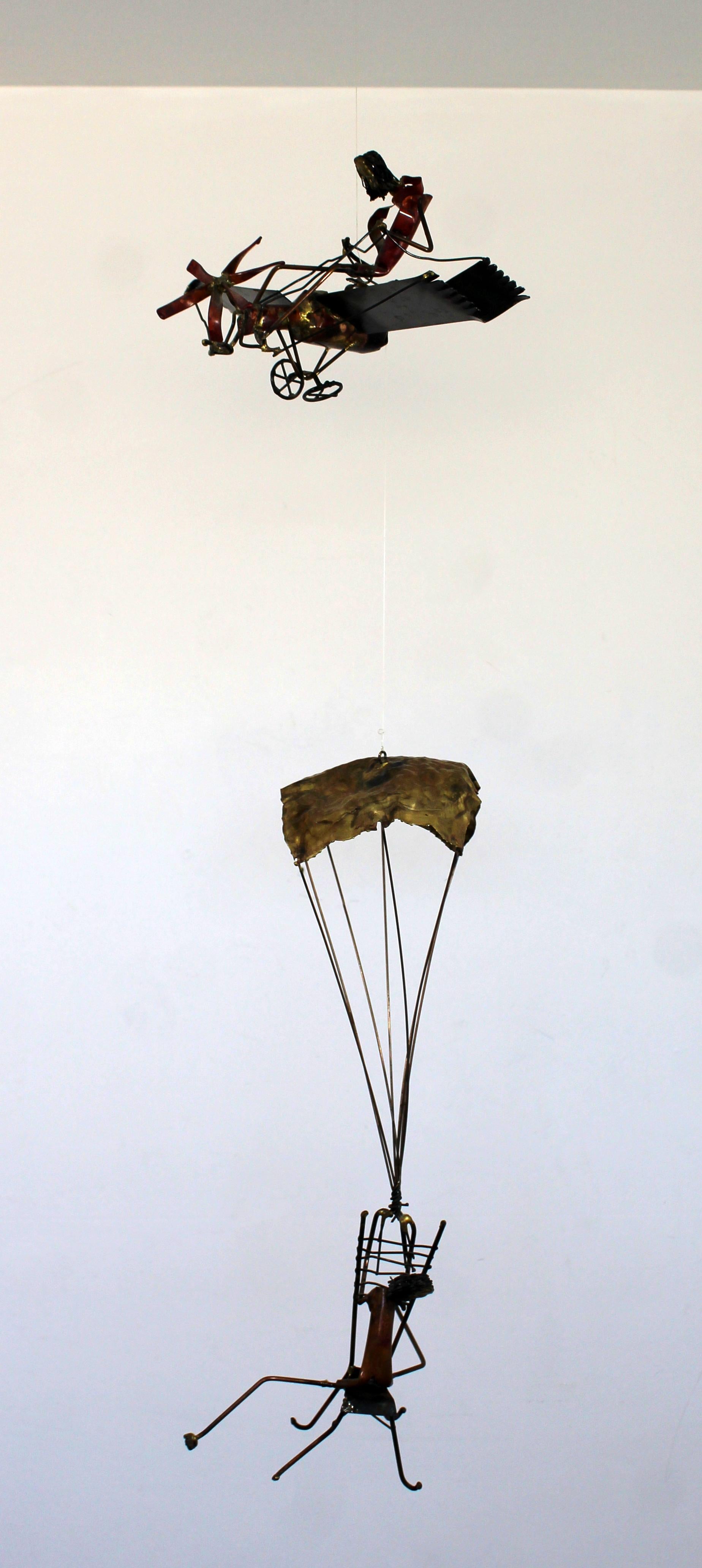 For your consideration is a whimsical, Brutalist brass wall sculpture of a man in a plane and a man hanging by a parachute beneath, in the style of Curtis Jere, circa 1970s. In excellent vintage condition. The dimensions are 12
