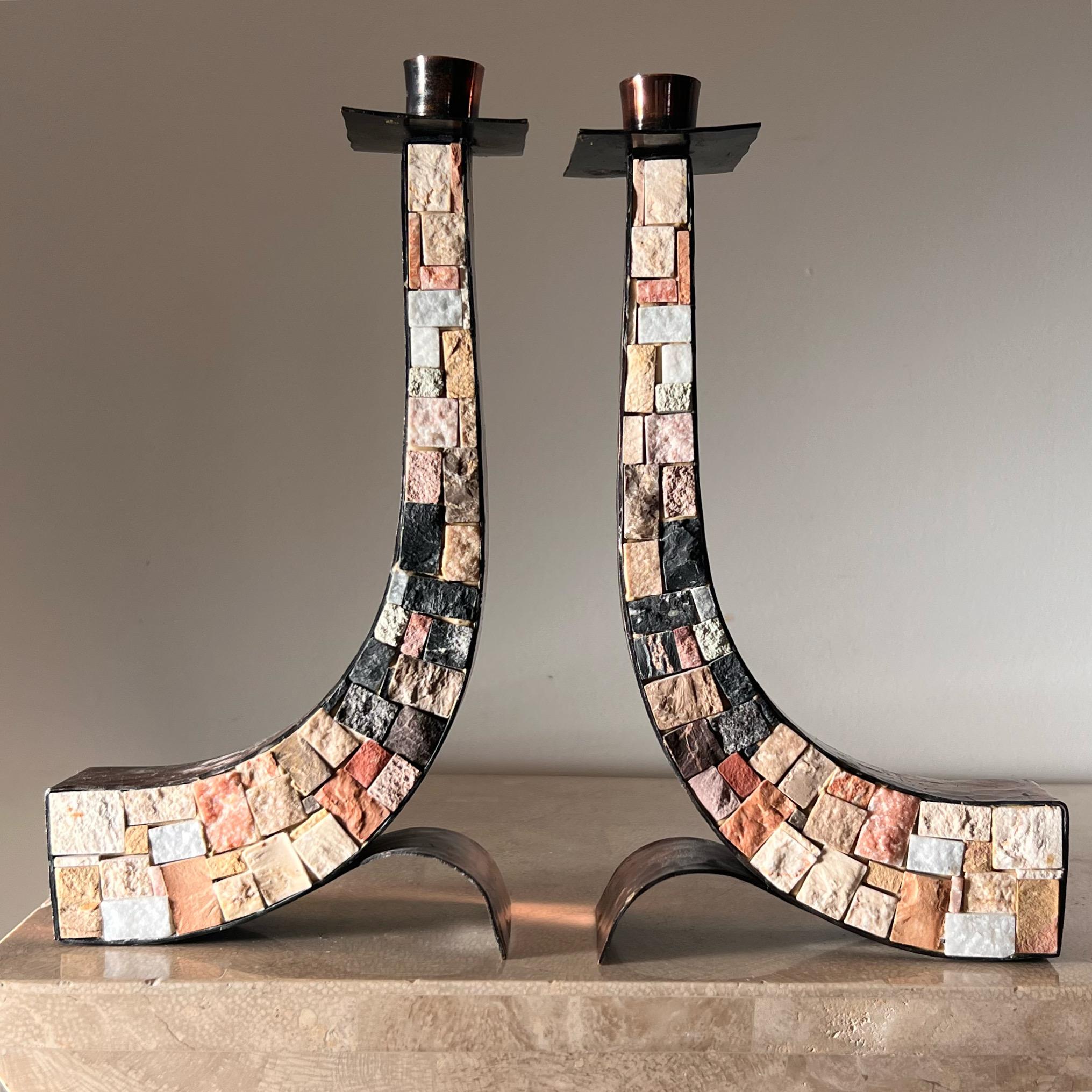 A stunning and unique pair of mid century modern candlesticks with decidedly brutalist sensibilities, circa late 1960s. Hand-worked copper comprises the frames of the candelaria, while a mosaic of stone fragments - limestone, marble, travertine, etc