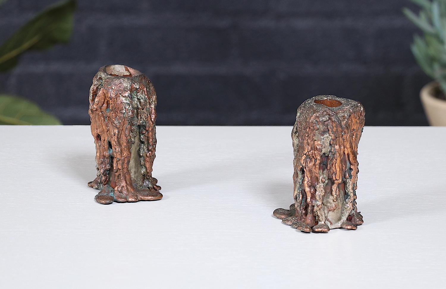 These Mid-Century Modern Brutalist candle holders bring an arresting sculptural presence to any space with their rugged, hand-forged copper construction. The raw, textured surfaces and organic, flame-kissed patina create a dramatic interplay of