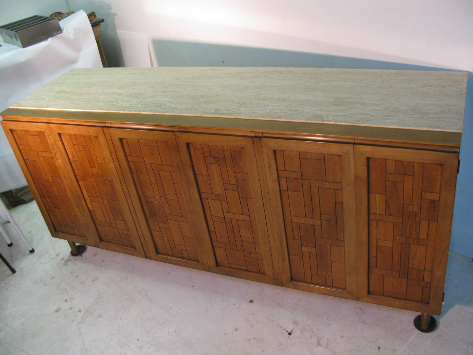 Fabulous credenza or dresser by Bert England. Walnut with travertine marble top, has 6 drawers which open to reveal 8 pull out drawers with sculpted handles. Brass stretcher and legs support the cabinet.