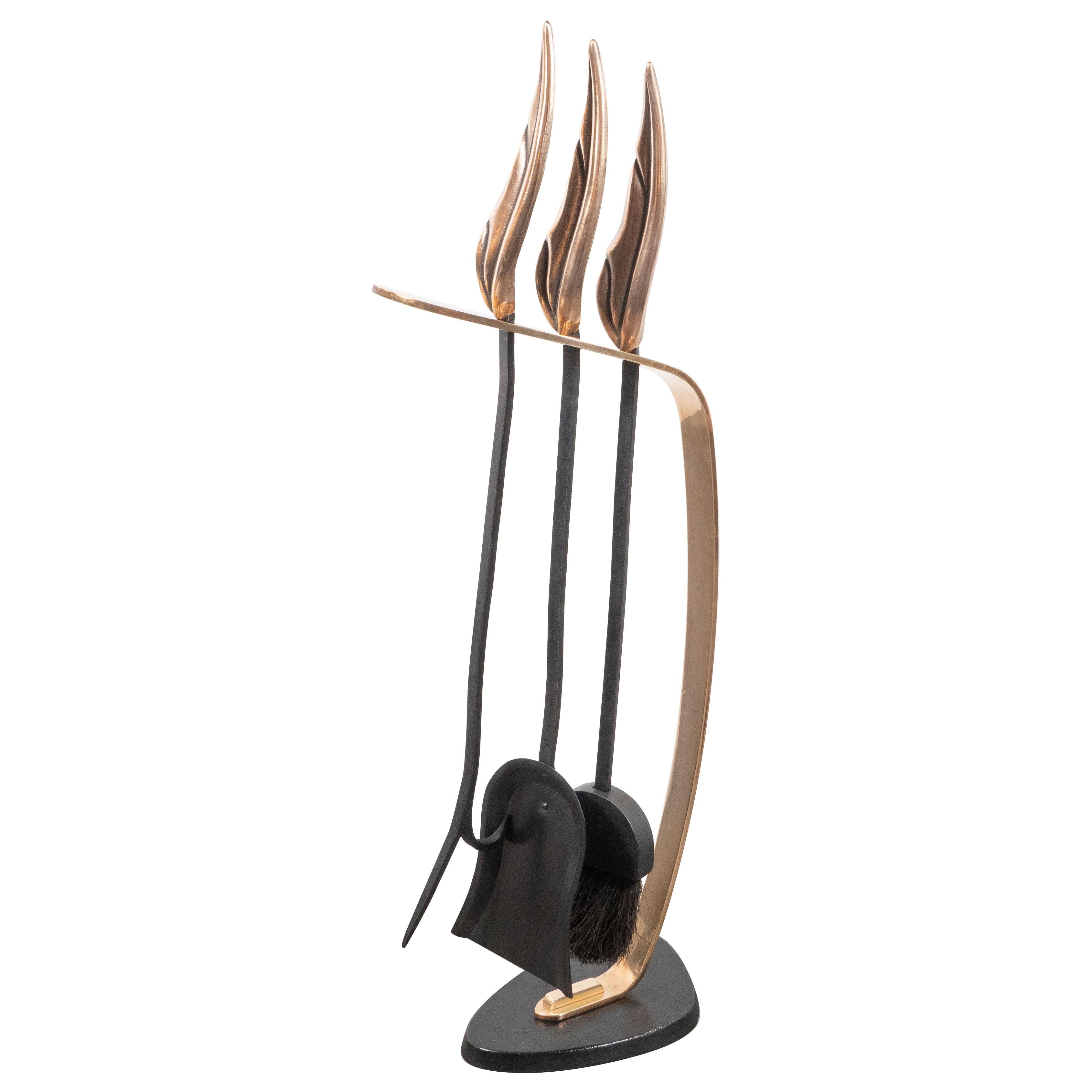 This stunning and dramatic Mid-Century Modern four piece fire tool set was realized in the United States, circa 1950. A cantilevered bronze support ascends from an amorphic shield form black enamel base that holds three tools (a poker, brush and