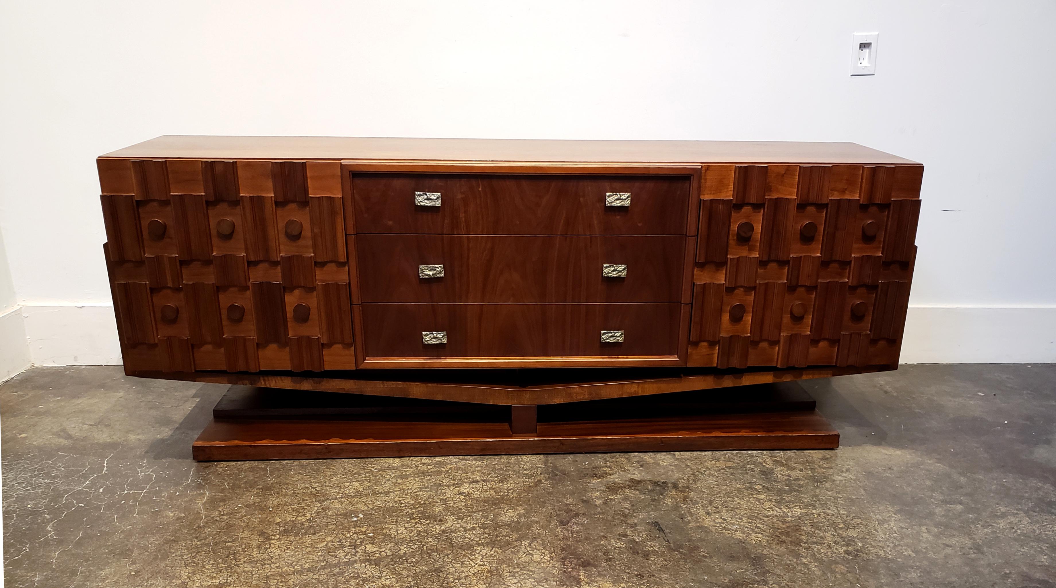 Beautifully-designed, Brutalist credenza raised on arched plinth with circular and beveled sculpted wood elements on side cabinet doors. Three large central drawers in warm walnut wood with cast iron Brutalist pulls. Side cabinets also have 3 small