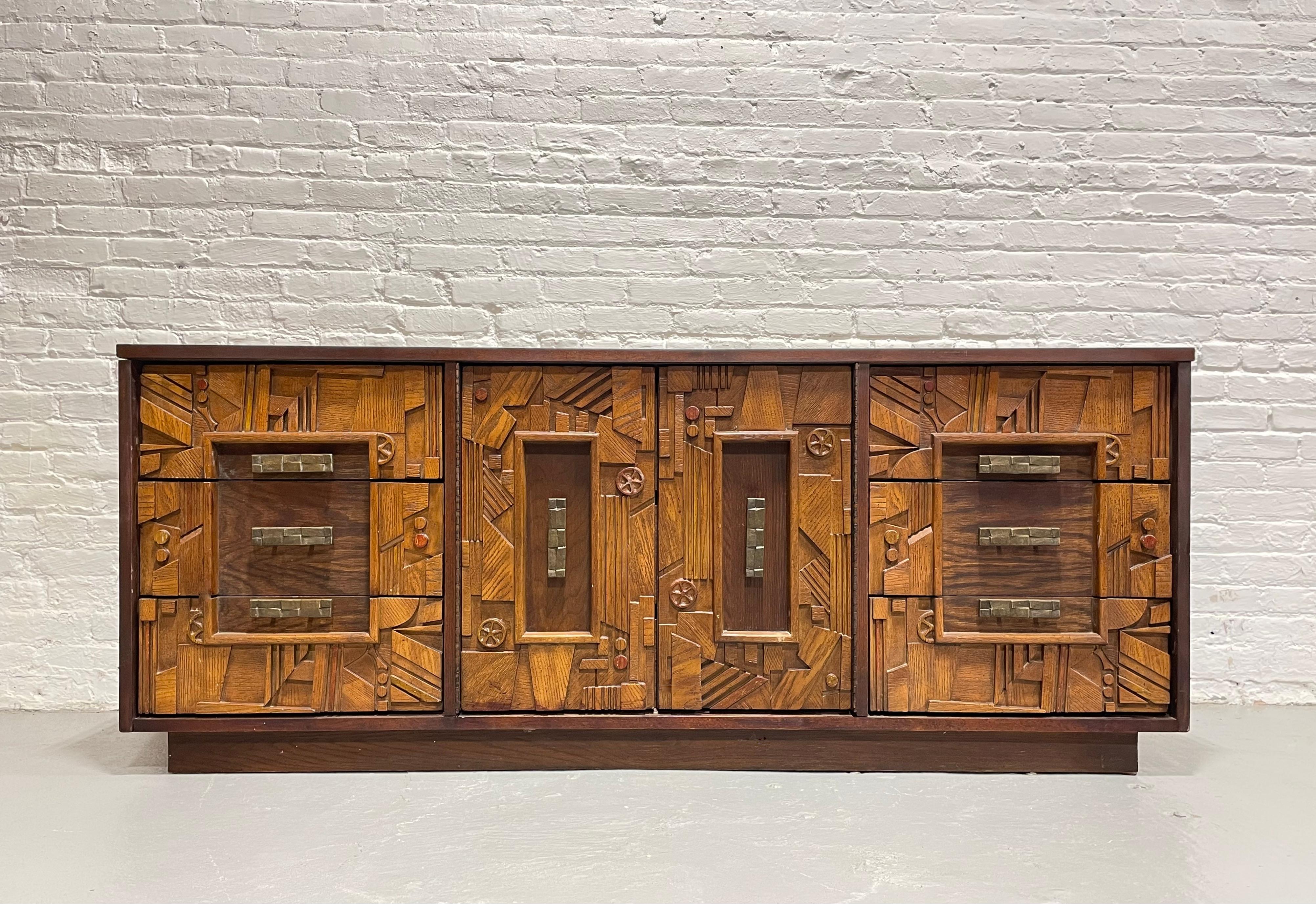 Mid Century Modern Long Dresser in a Paul Evans Brutalist style, c. 1960’s. The façade consists of a highly textured pattern of rough hewn shapes and each piece was carefully sculpted from solid wood with brutalist, pueblo inspired carvings.  Loads