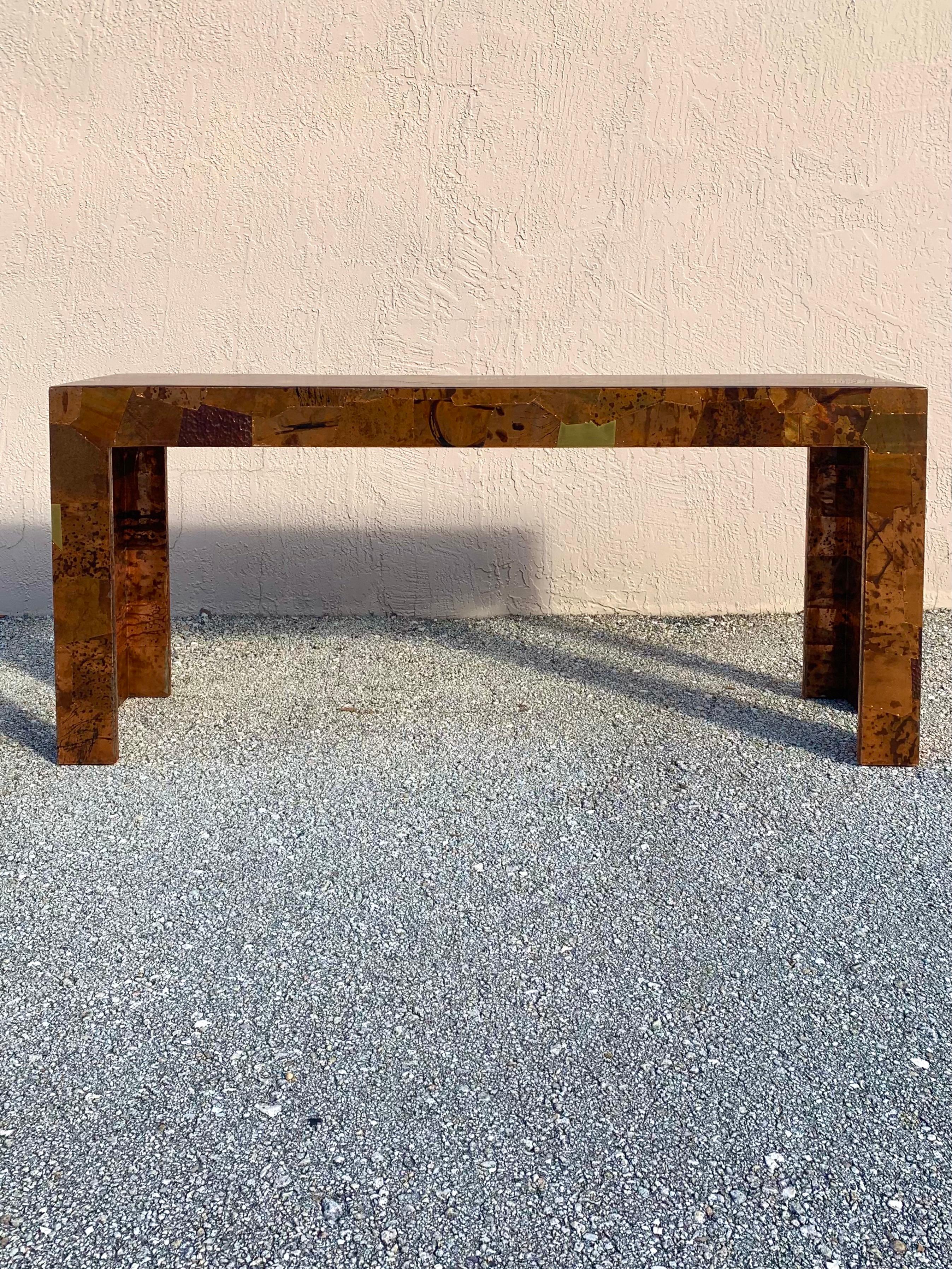 Studio made copper and brass console table. Made to have a brutalist flair the artist used different pieces of textured and patinated copper and clean brass to cover the entire console table. The plates are affixed with copper staples then covered